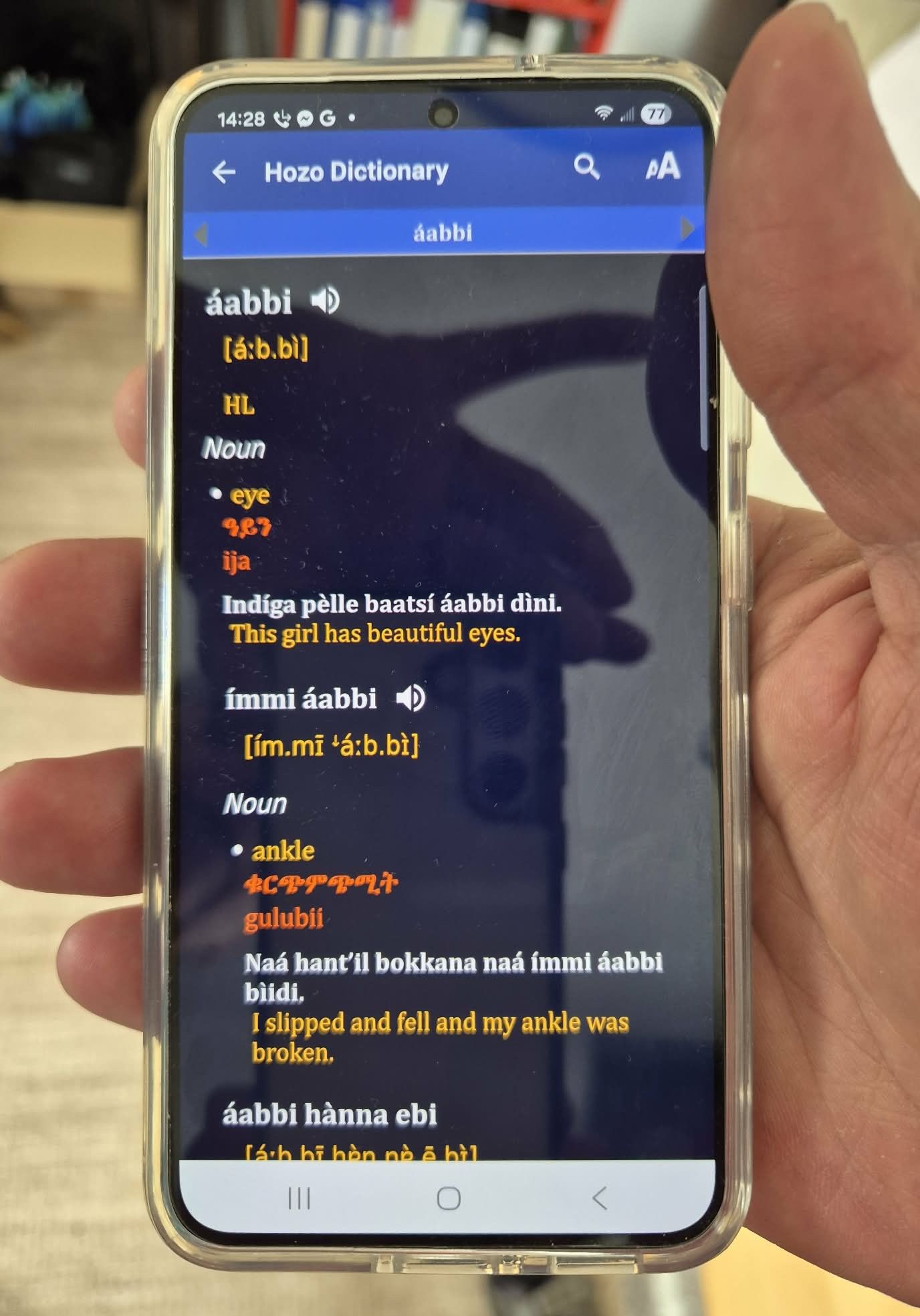 Bildet viser en mobiltelefon som viser fram ordbok-appen for hozo-språket