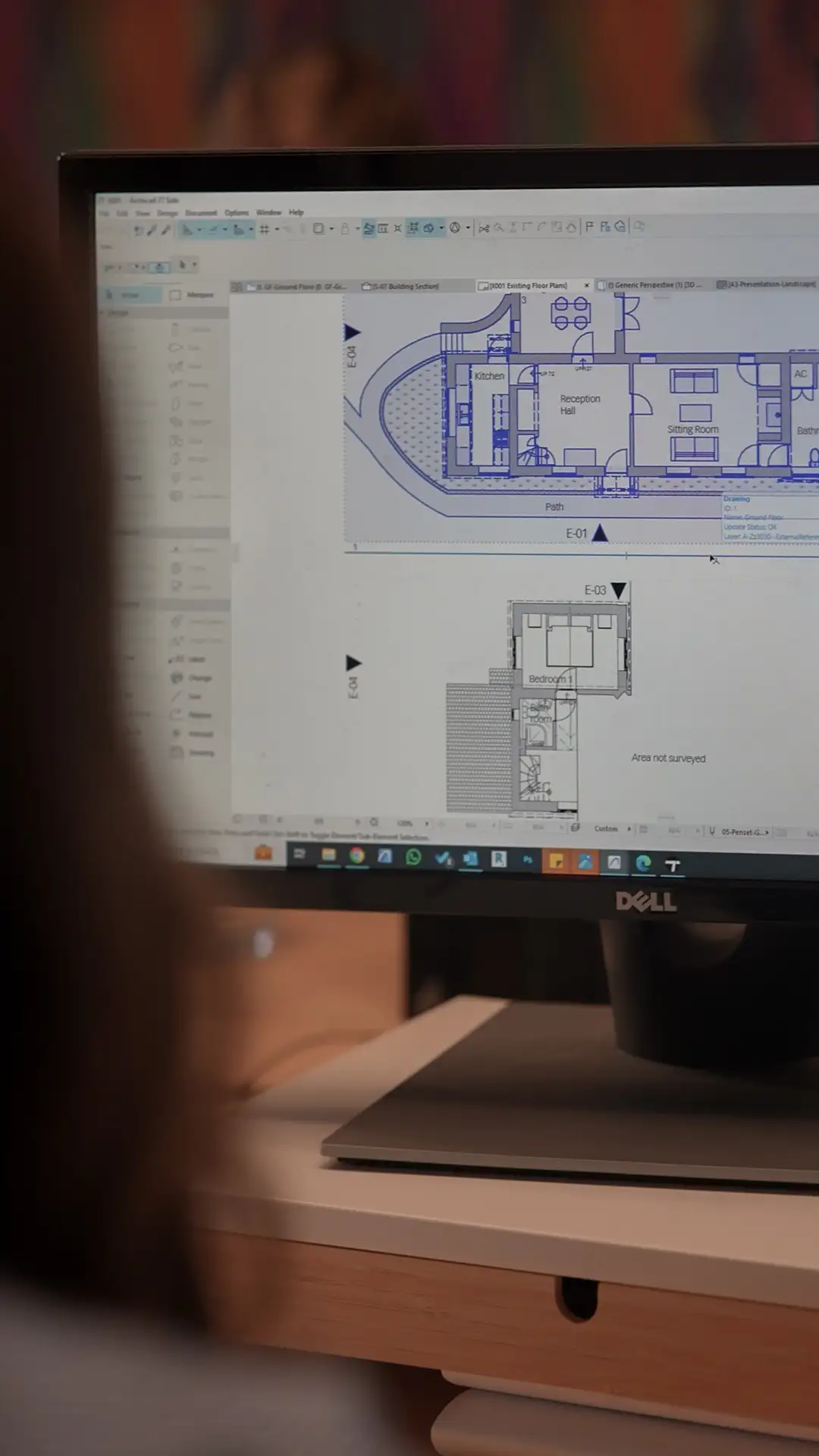 A lady with brown hair looking at computer screen showing architects planning drawings detailed with blue lines.