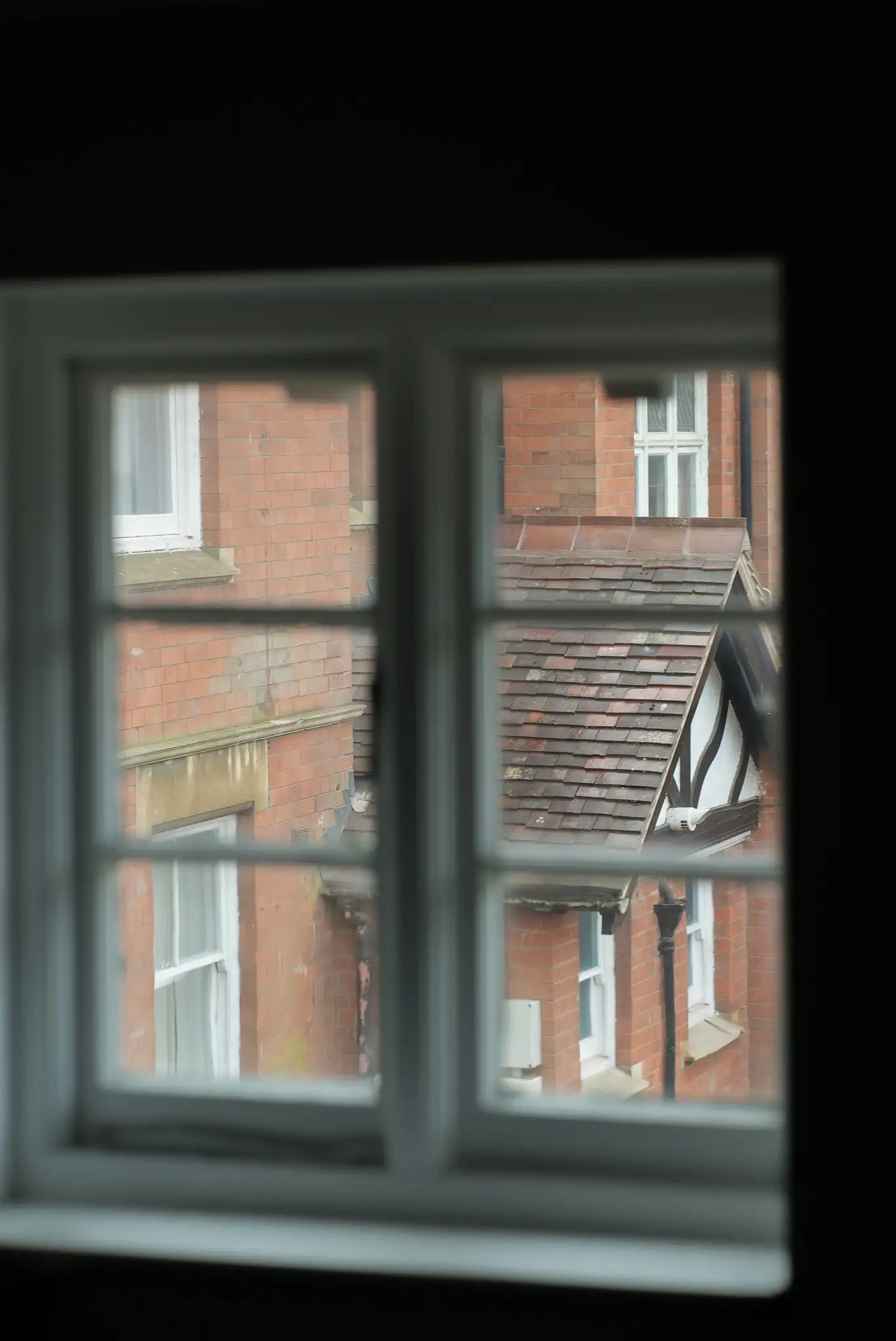 An artistic shot of buildings through an old style window.