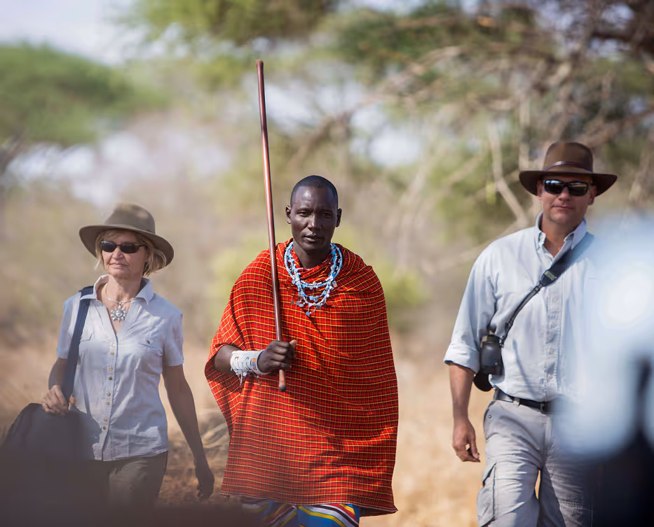 A Maasai guide navigates African savannah tourists through authentic cultural experience.