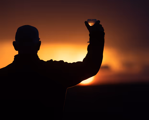 A man captures the vibrant orange sunset with his silhouette against sky colors.