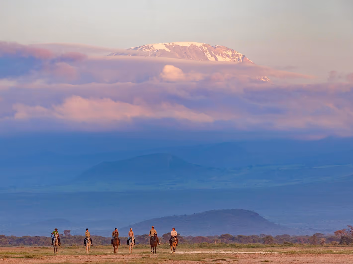 Horseback riders on Kenyan savannah with Mount Kilimanjaro breathtaking African safari landscape.