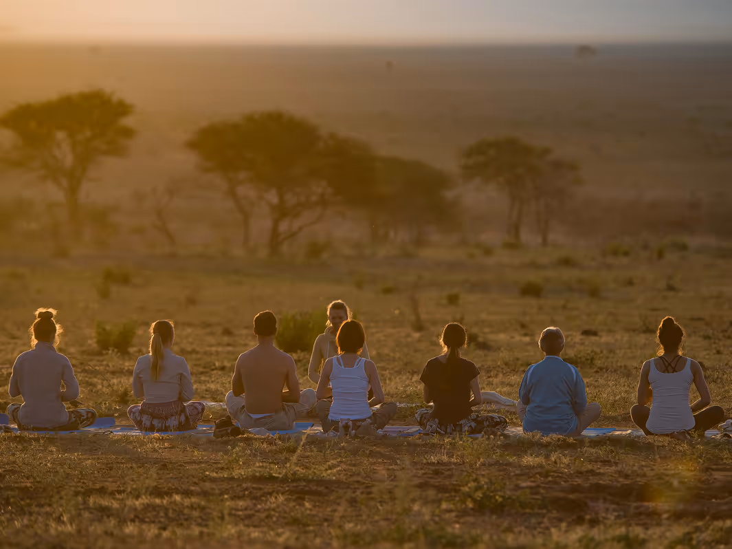 Serene savannah sunset scene featuring people meditating in peace outdoors with yoga practice.