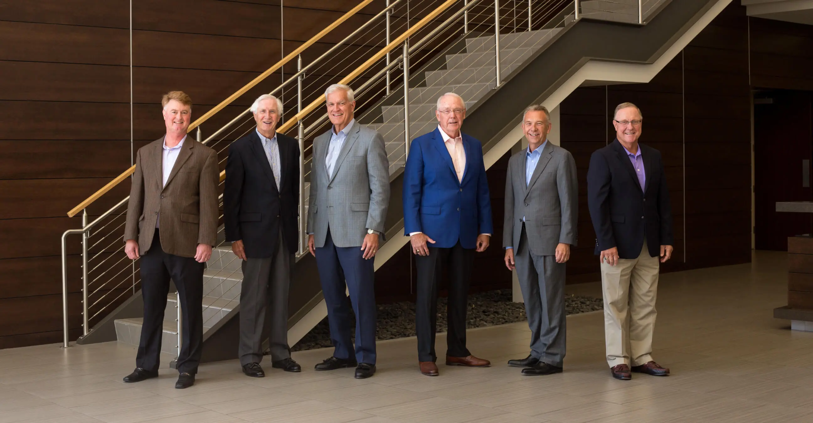 Group of suited professionals standing on stairs.