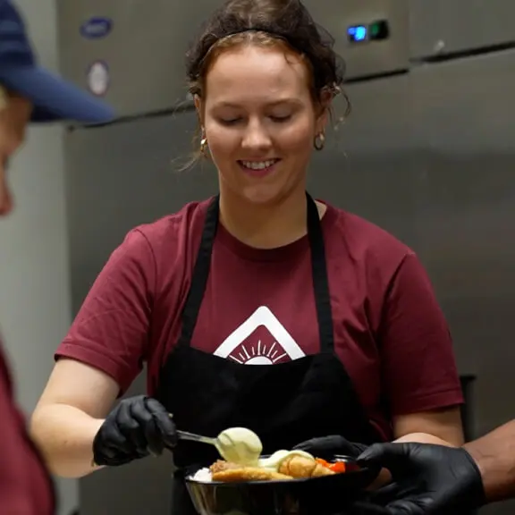Woman smiling while serving food.