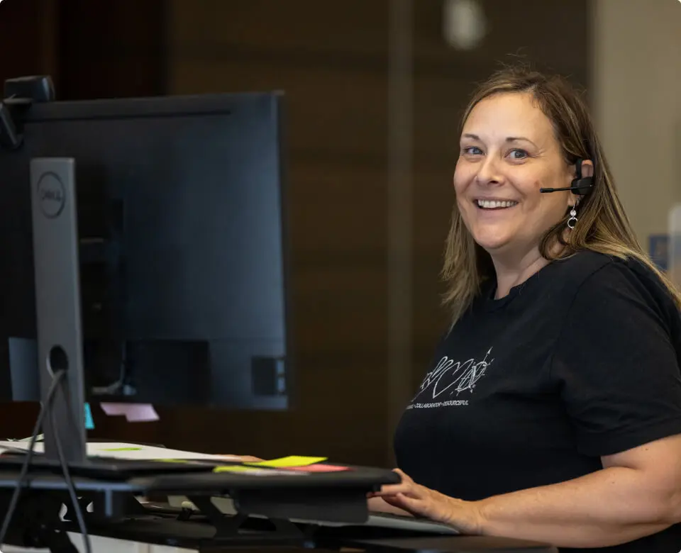 Smiling woman seated in a classroom or training space.