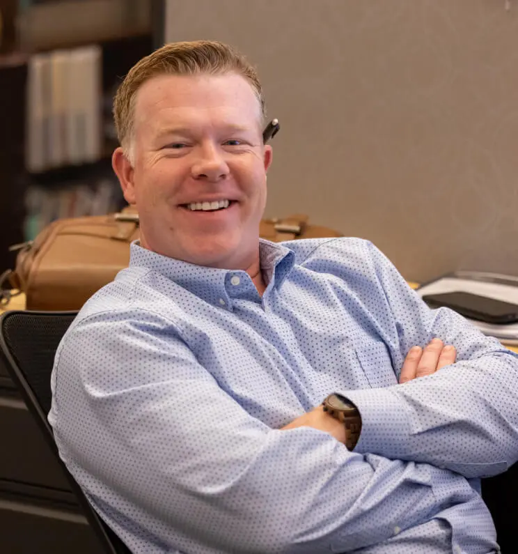 Man leaning back and smiling in a suit at his desk.