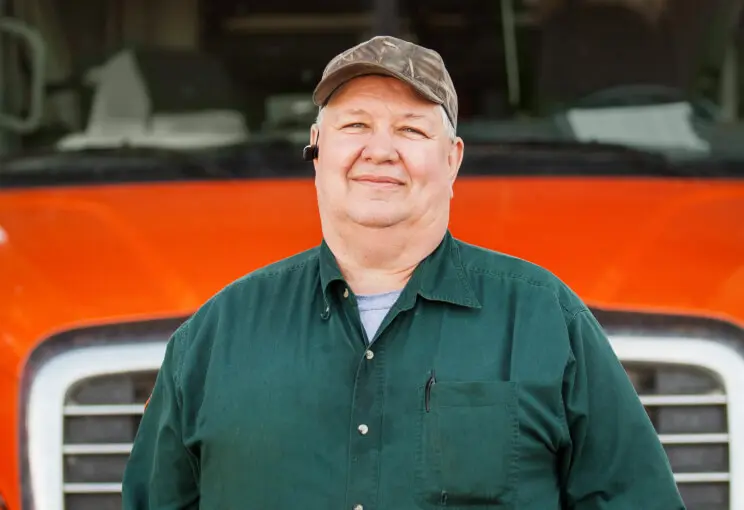 Smiling man in front of a red semi-truck.