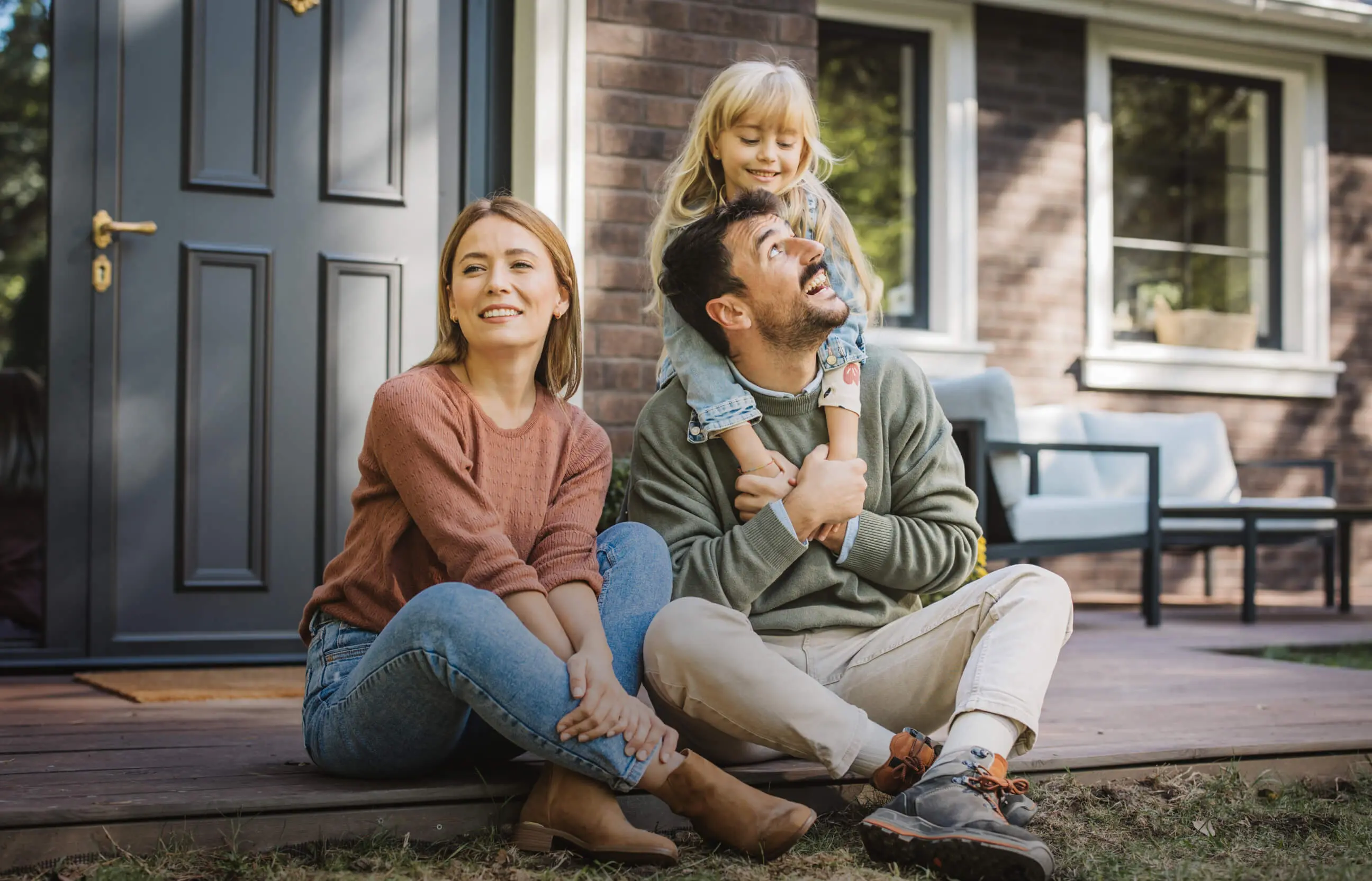Parents sitting casually outside a home.