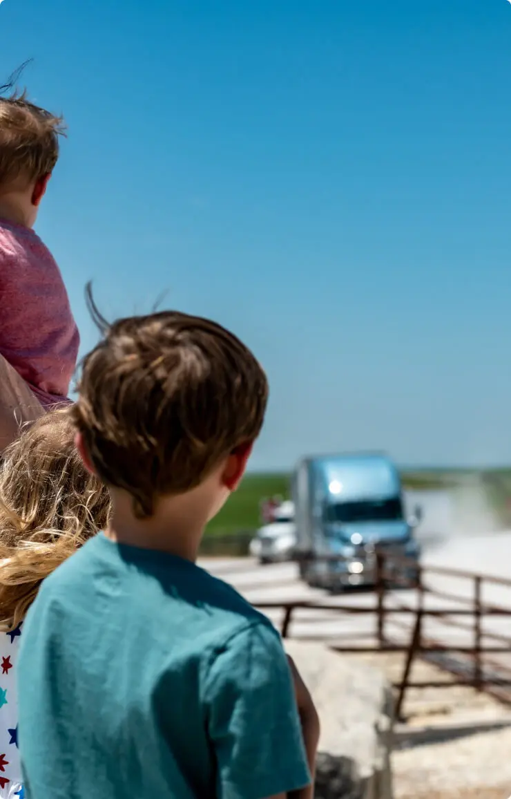 Child looking up at a person demonstrating machinery outdoors.