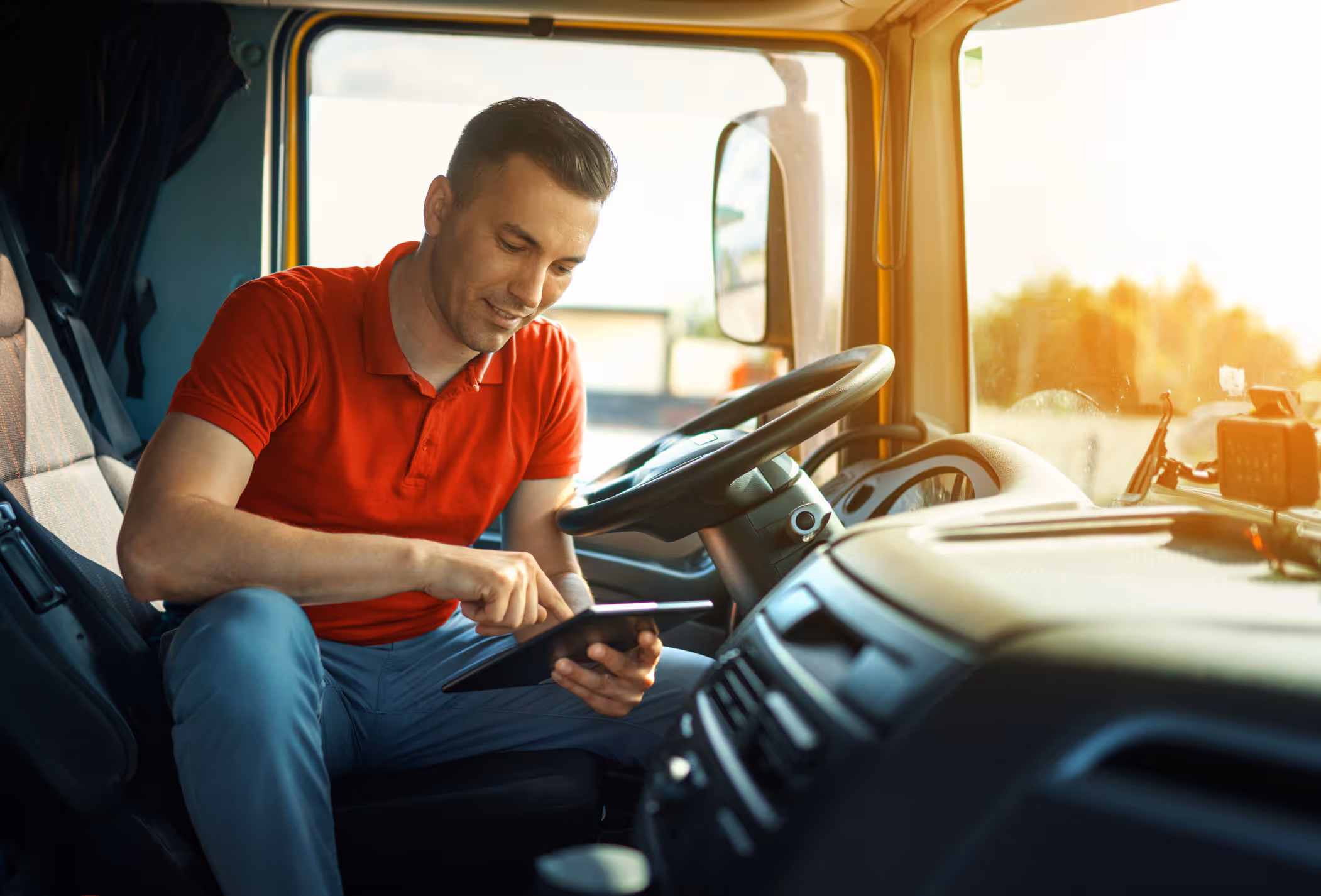 Man using iPad in cab of truck.