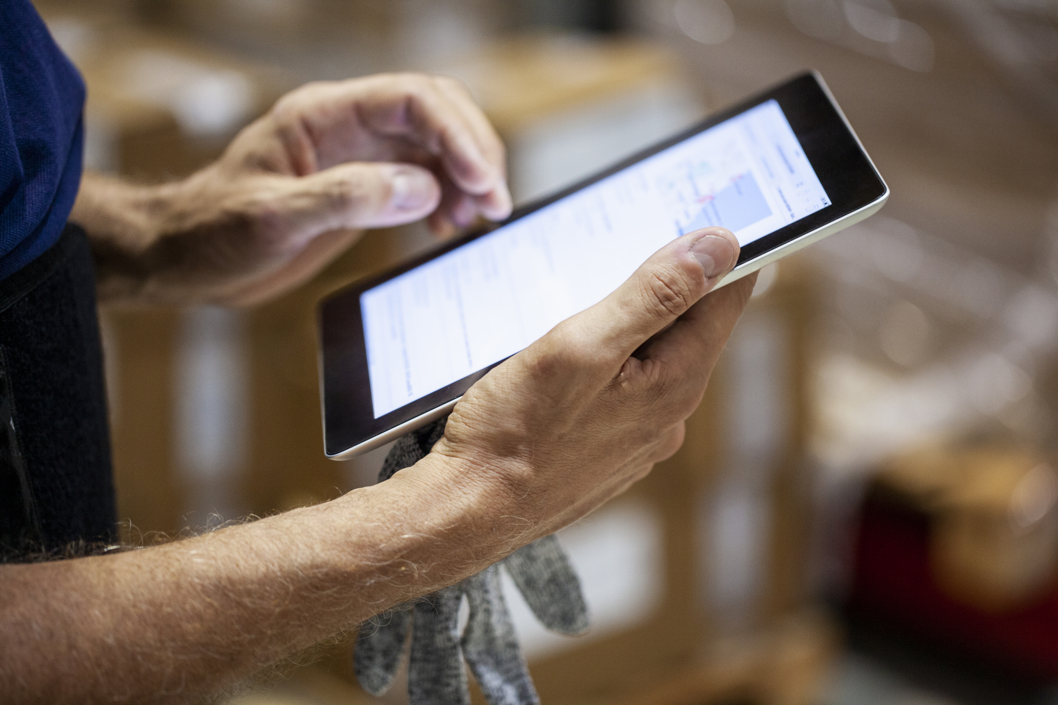 ipad in hands also holding a work glove
