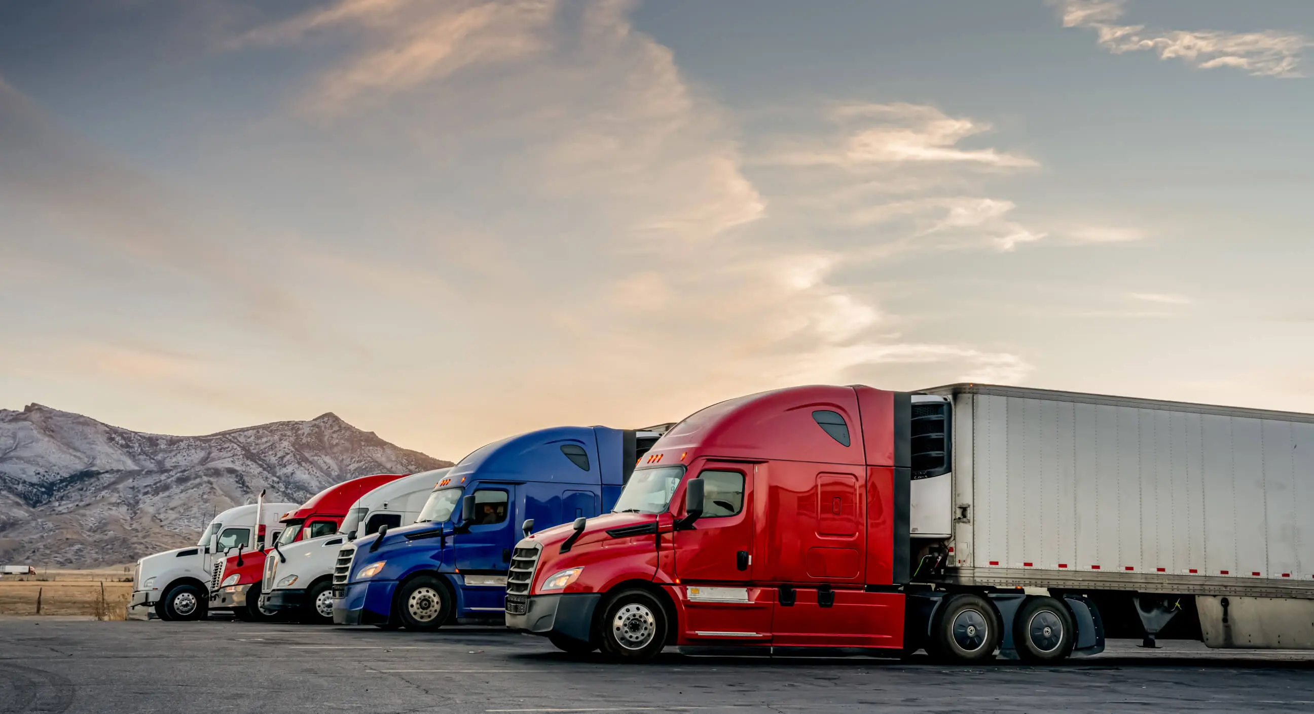 Photo of trucks on a parking with mountains in the background.
