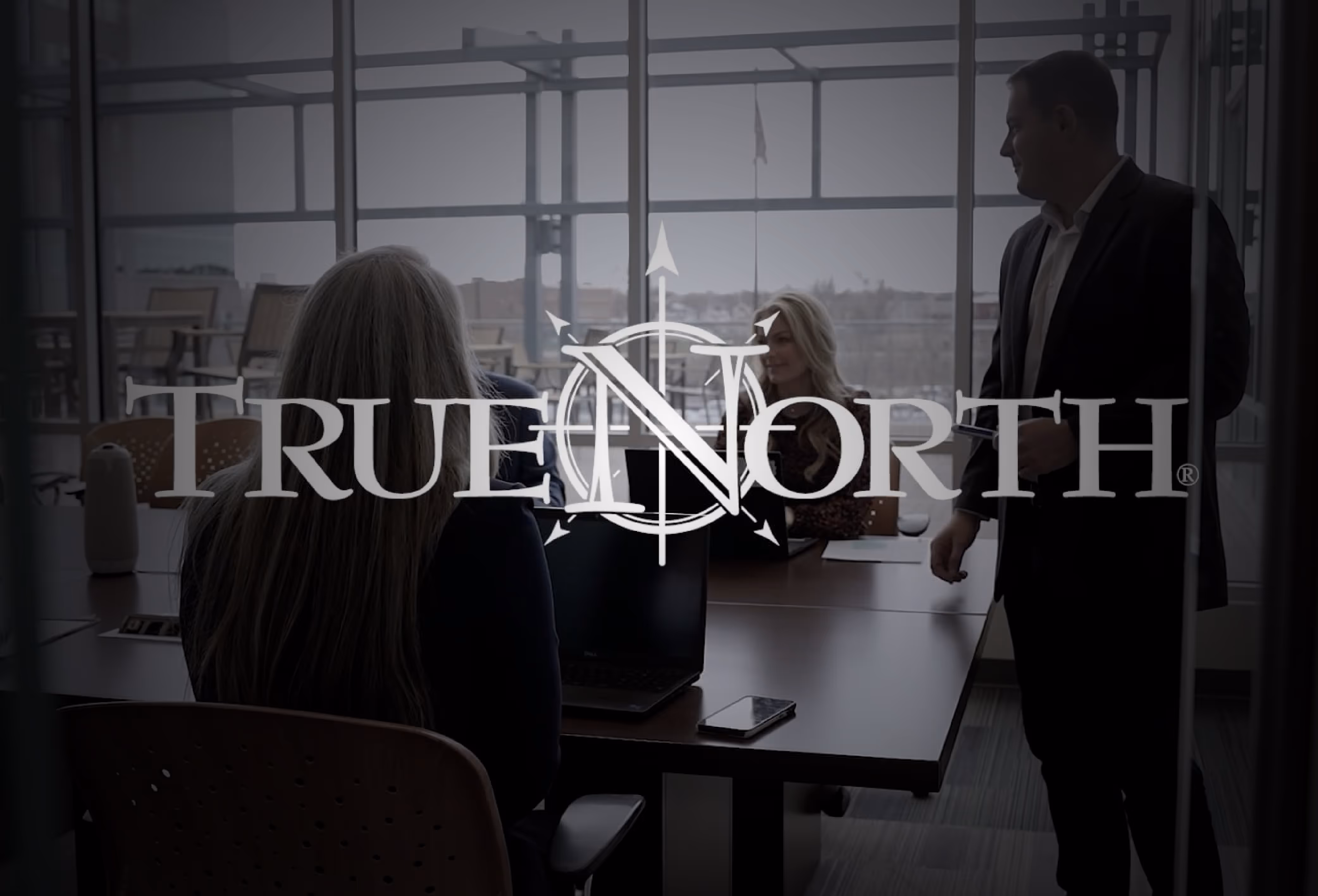 TrueNorth logo positioned over employees meeting in conference room