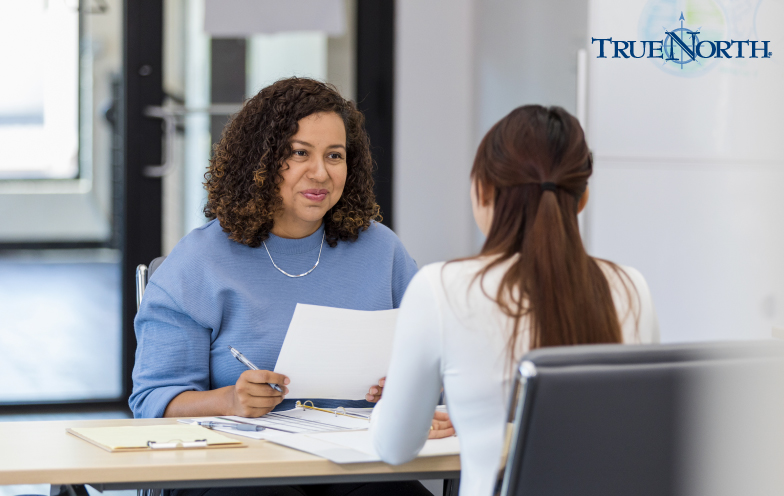 HR staff member sits down with an employee at a desk