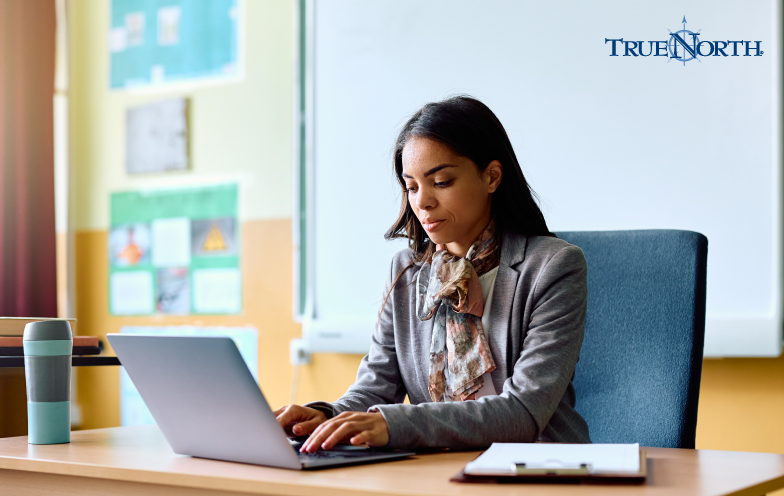 A teacher at a computer in a classroom setting