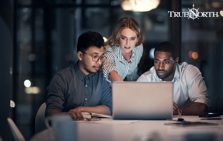 Group of colleagues gather around a computer.