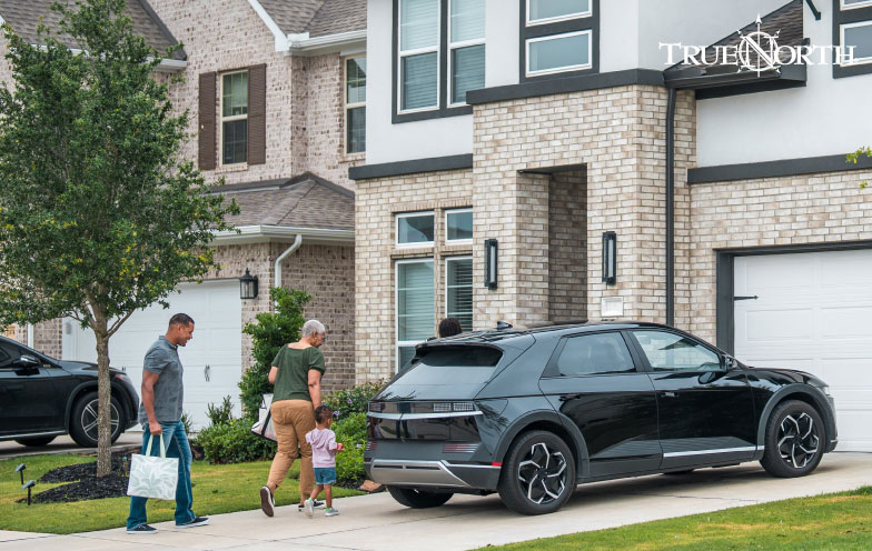 People standing in front of a car in a driveway.