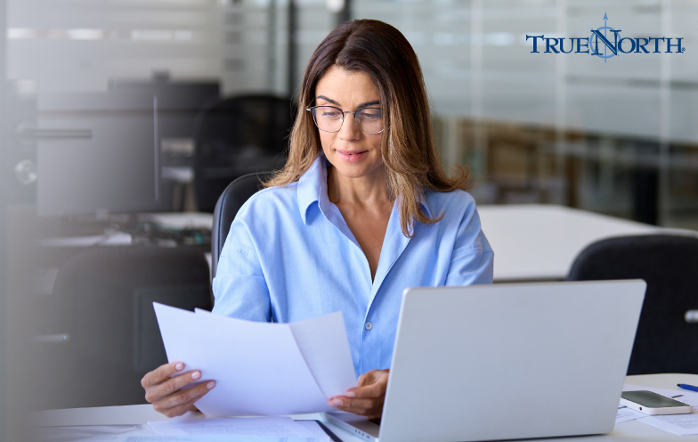 Woman examining documents in front of a computer