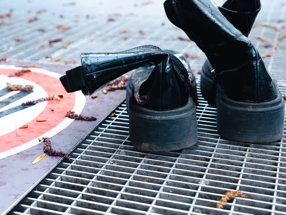 a pair of black boots on a metal grate