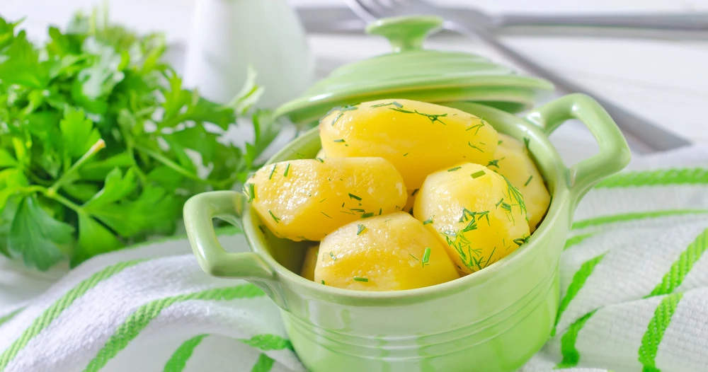 Fresh potatoes on wooden cutting board with healthy cooking ingredients