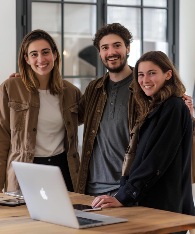 Three individuals gathered around a laptop, engaged in discussion or collaboration.