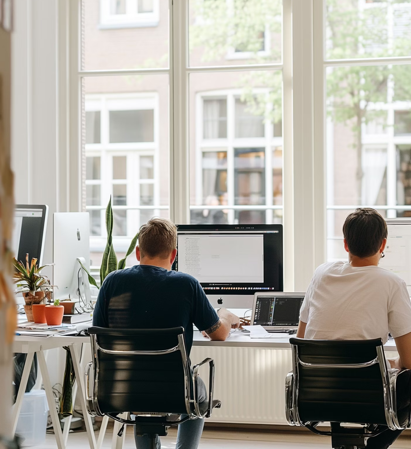 A man and woman standing together in front of a computer, engaged in discussion or collaboration.
