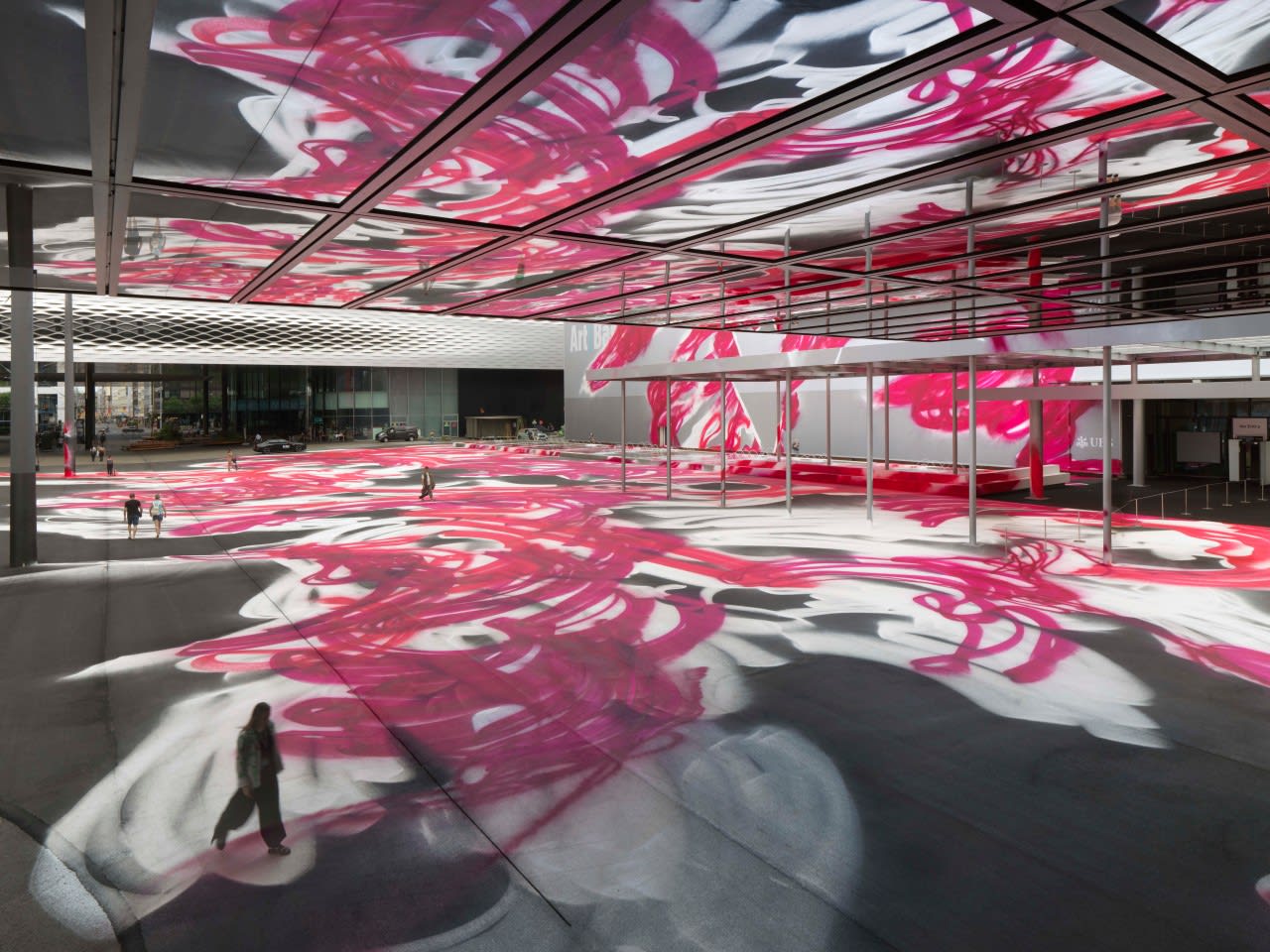 Art installation "CHOIR" (2025) by Katharina Grosse at Messeplatz during Art Basel 2025, featuring vibrant pink and white spray-painted patterns covering the square and reflecting on the ceiling.
