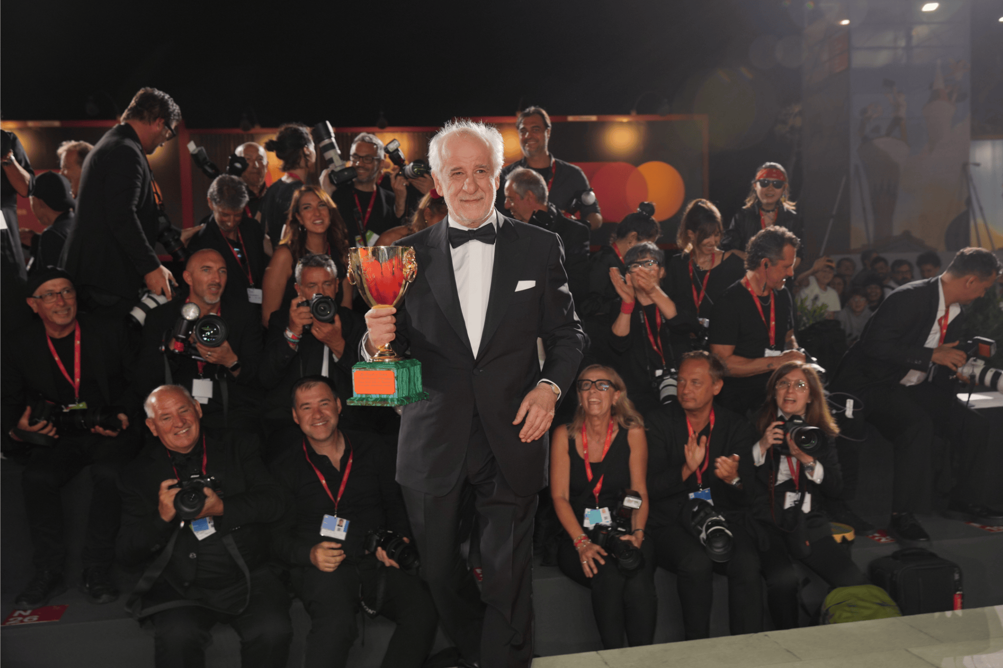 Italian actor Toni Servillo holds the Coppa Volpi for Best Actor at the 82nd Venice International Film Festival 2025, smiling as he poses in front of applauding photographers on the red carpet.