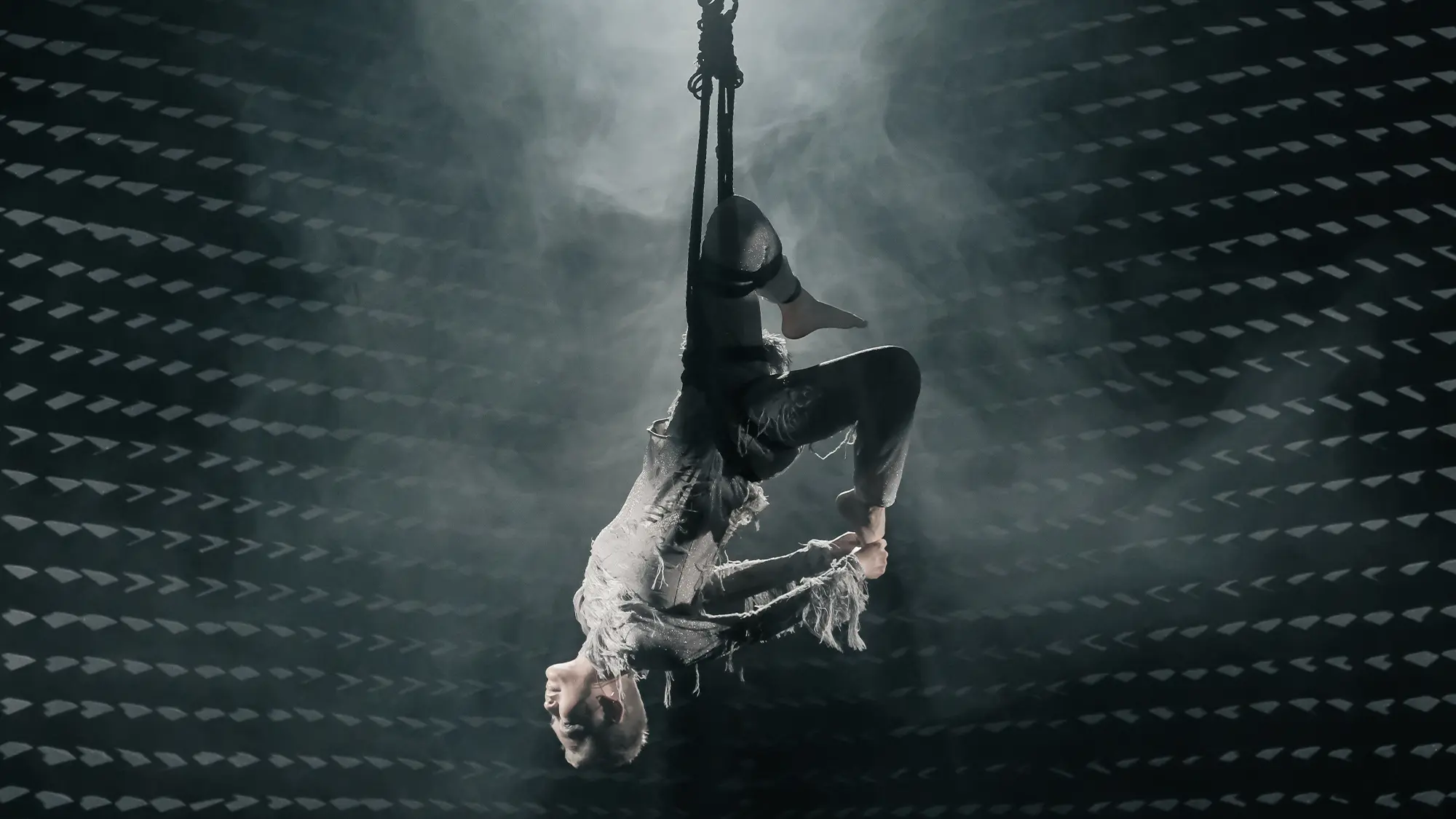 Artist Angela Su suspended upside down in mid-air during her haunting aerial performance at Frieze Seoul 2025, enveloped in dramatic lighting and mist.