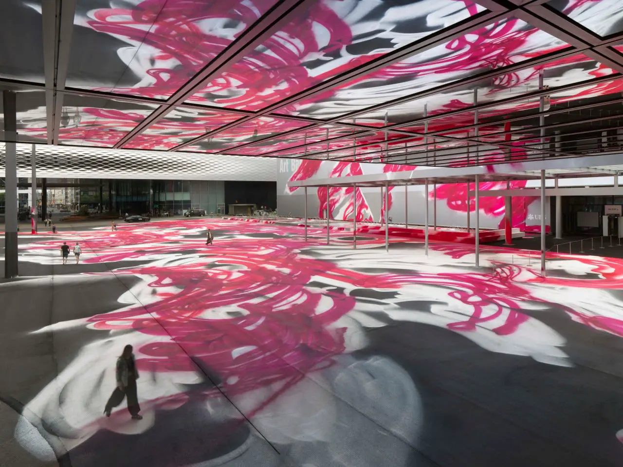 Art installation "CHOIR" (2025) by Katharina Grosse at Messeplatz during Art Basel 2025, featuring vibrant pink and white spray-painted patterns covering the square and reflecting on the ceiling.