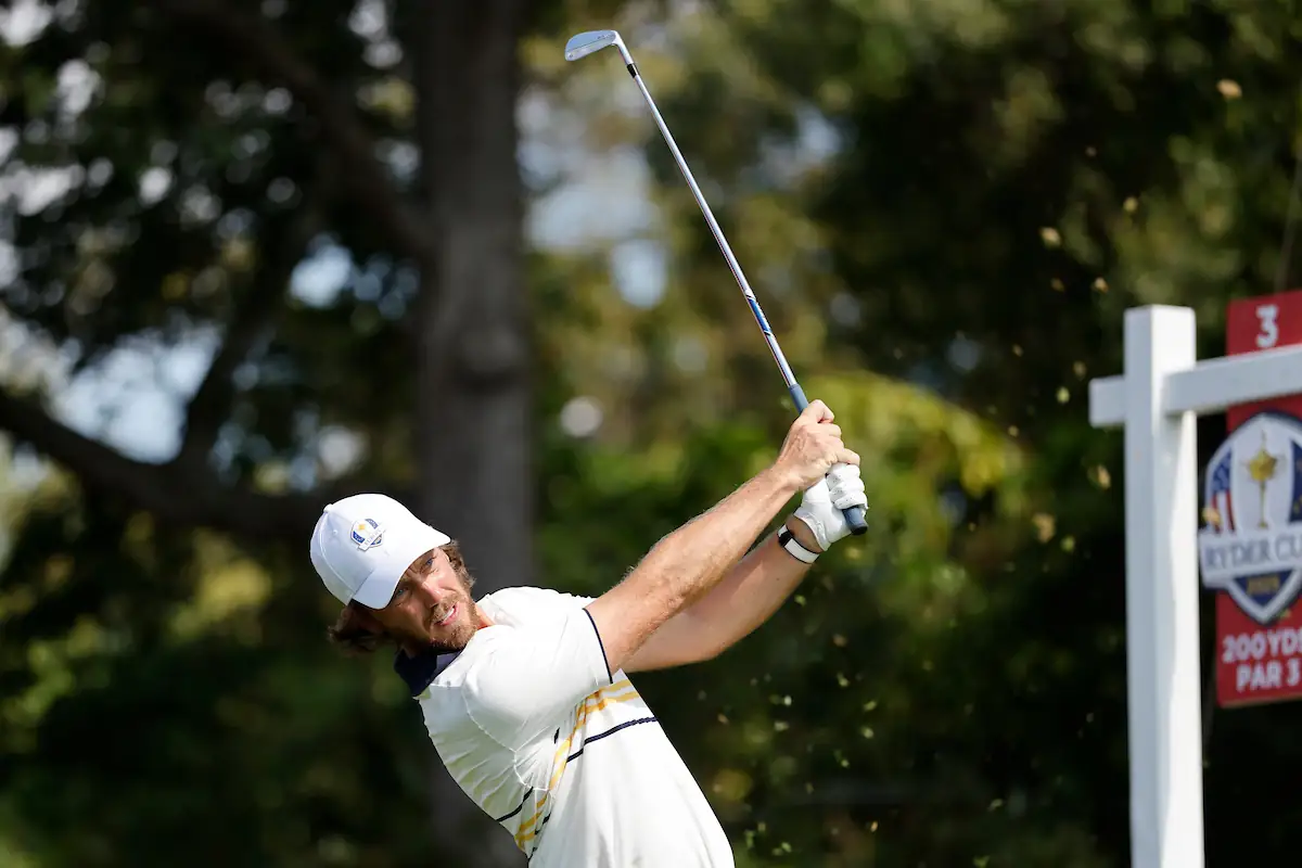 Team Europe’s Tommy Fleetwood executes a powerful iron shot on the 3rd hole at Bethpage Black during the 2025 Ryder Cup, wearing the European team uniform under sunny skies.