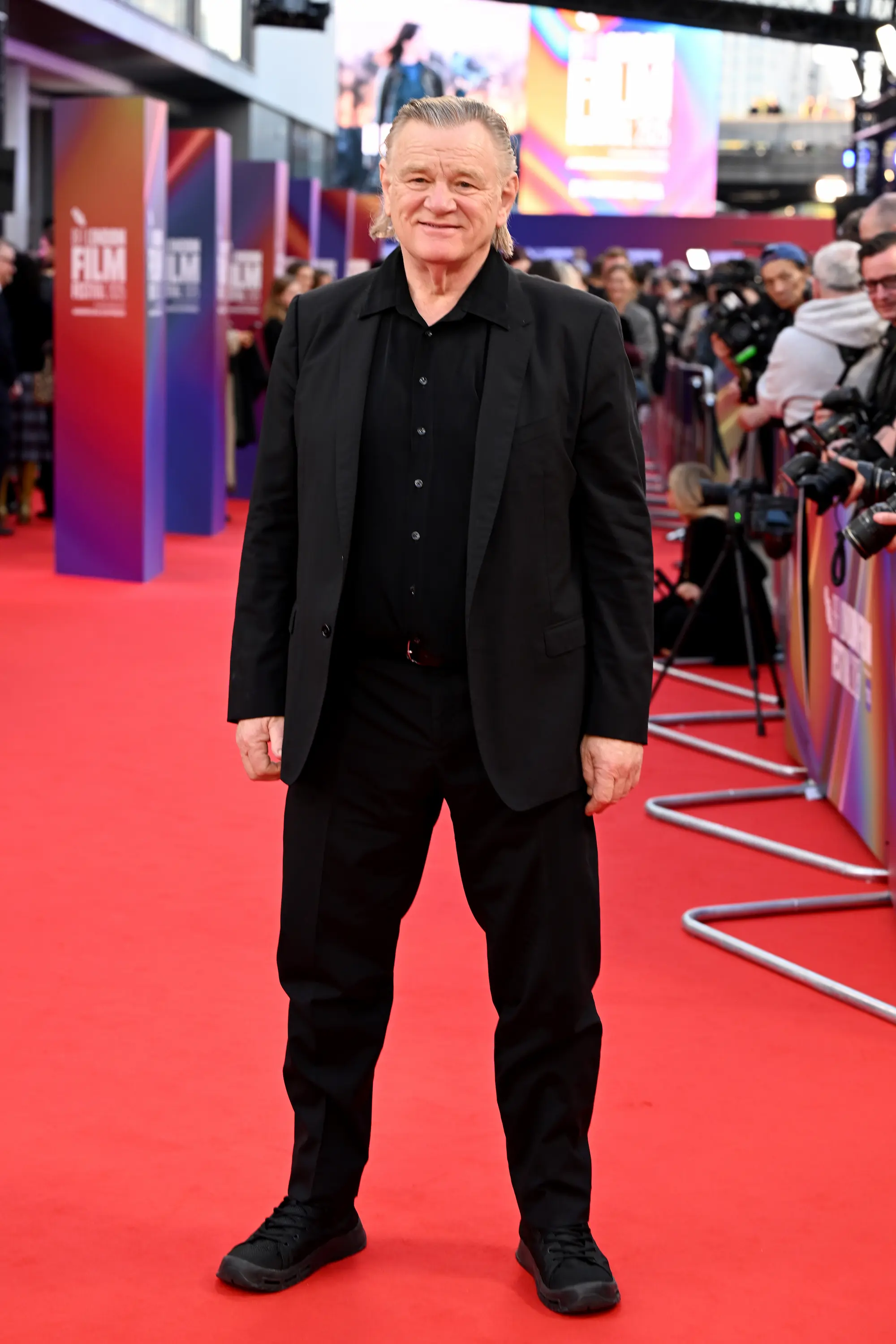Brendan Gleeson poses on the red carpet at the BFI London Film Festival 2025, wearing an all-black suit and smiling for photographers during the premiere event.