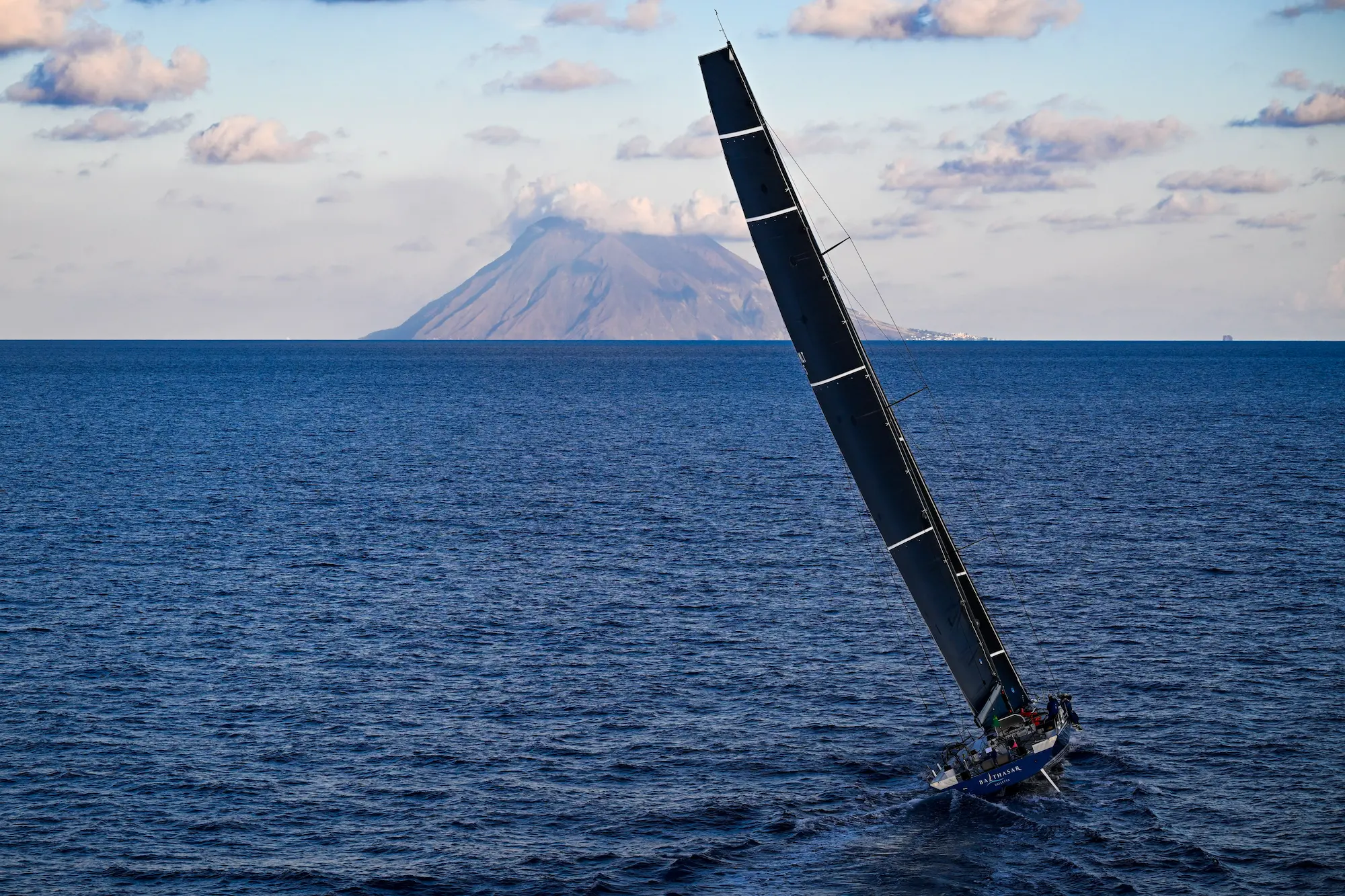 Aerial view of superyachts Balthasar and Black Jack competing in the Rolex Middle Sea Race on deep blue Mediterranean waters.