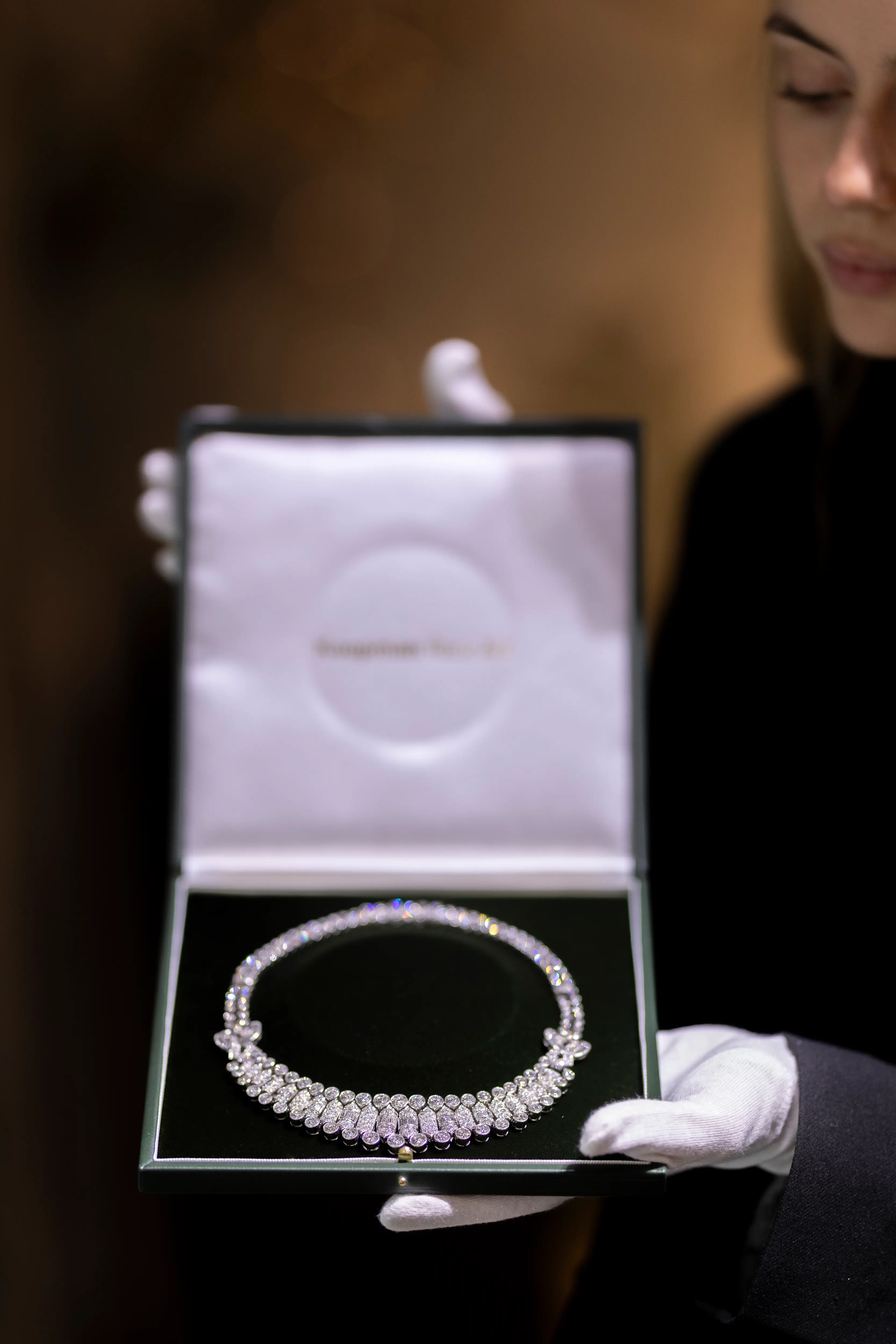 A gloved art handler presents an elegant diamond necklace in a display box at the LAPADA Art & Antiques Fair 2025 in London, showcasing Koopman Rare Art’s fine jewelry craftsmanship.