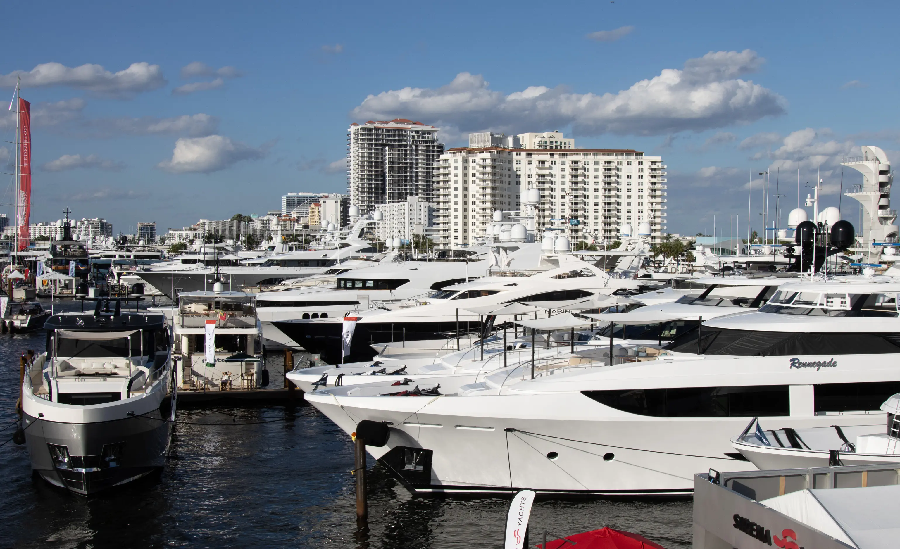 A view of luxury yachts docked at the Fort Lauderdale International Boat Show 2025, set against the city skyline under a bright blue sky.