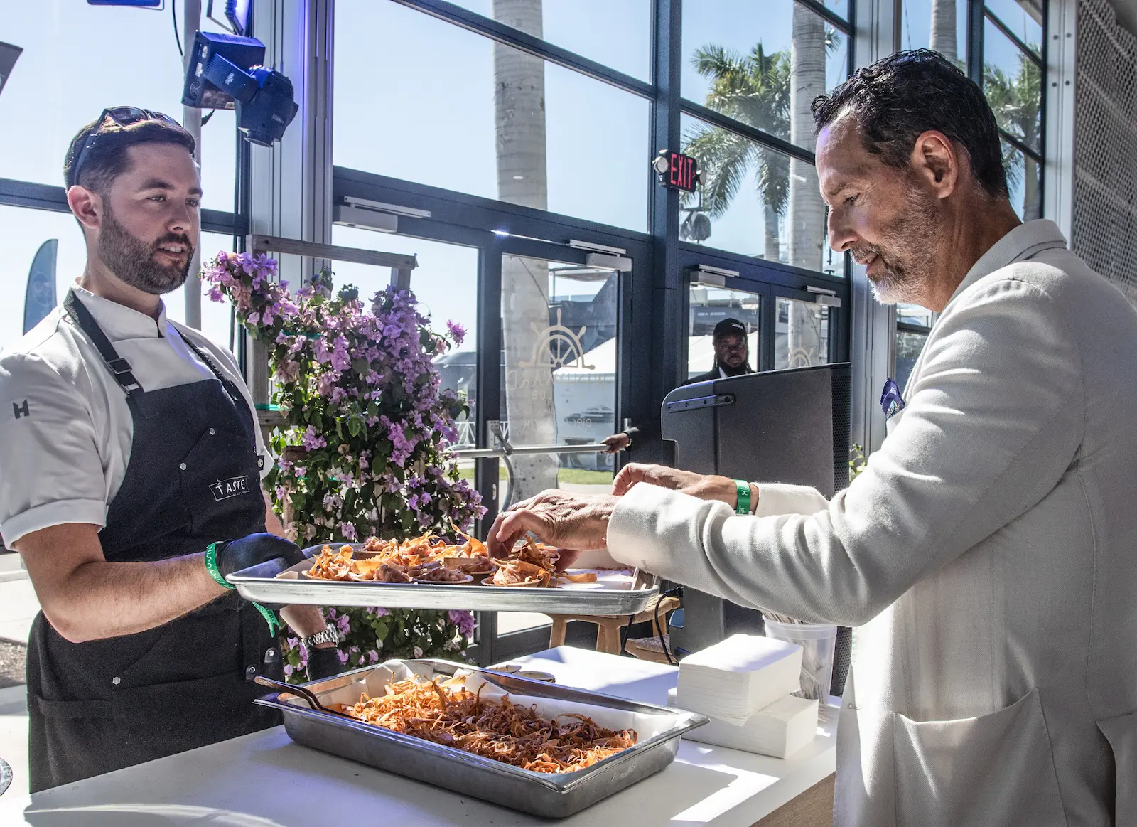 A chef serves gourmet dishes to a guest inside a sunlit lounge at the 2025 Fort Lauderdale International Boat Show, highlighting the event’s exclusive culinary offerings.