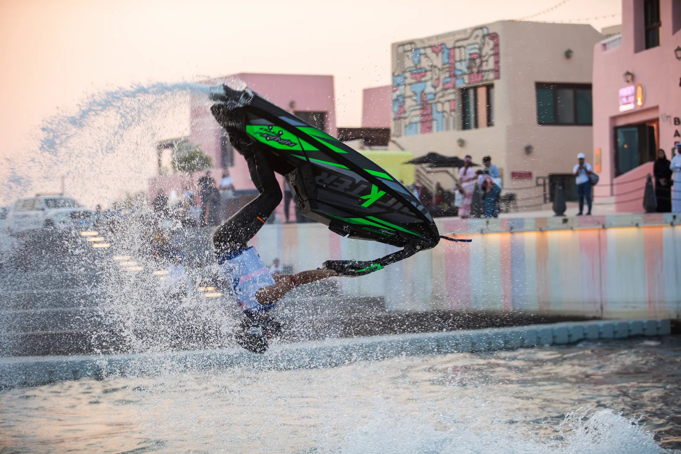 A professional jet ski rider performs an aerial flip during an action-packed water show at the Qatar Boat Show 2025 in Old Doha Port, entertaining spectators along the waterfront.
