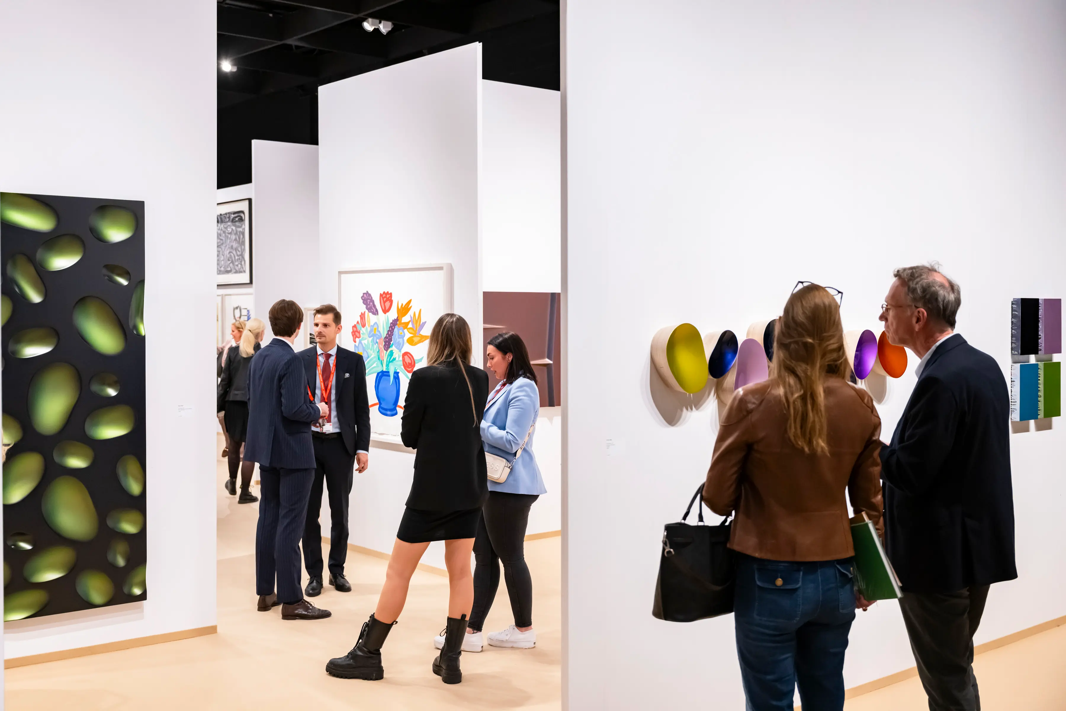 Guests and collectors explore modern and contemporary artworks at Art Cologne 2025, surrounded by vibrant paintings and sculptural installations inside Koelnmesse’s exhibition halls.