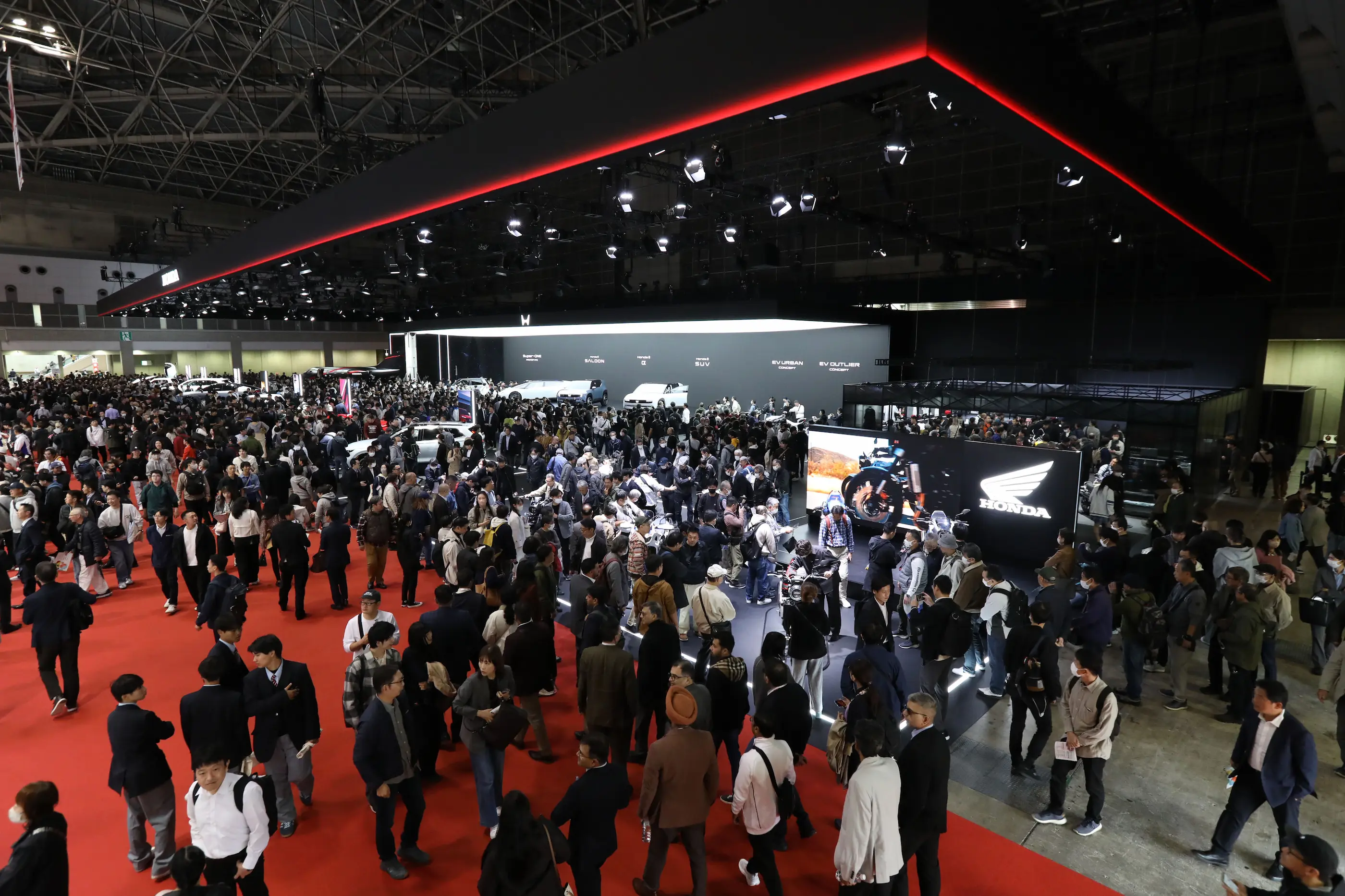 Visitors fill the exhibition halls at the Japan Mobility Show 2025 in Tokyo, viewing displays from major automakers like Honda showcasing the future of mobility and innovation.