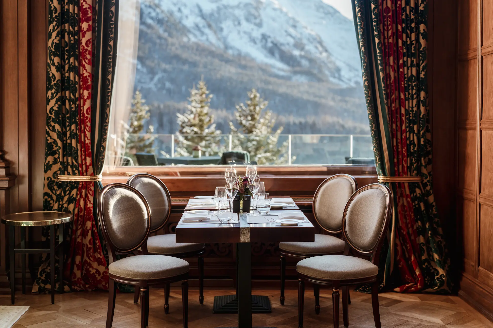 Intimate dining table for four at Carlton Hotel restaurant with elegant place settings and mountain views through large windows with ornate curtains