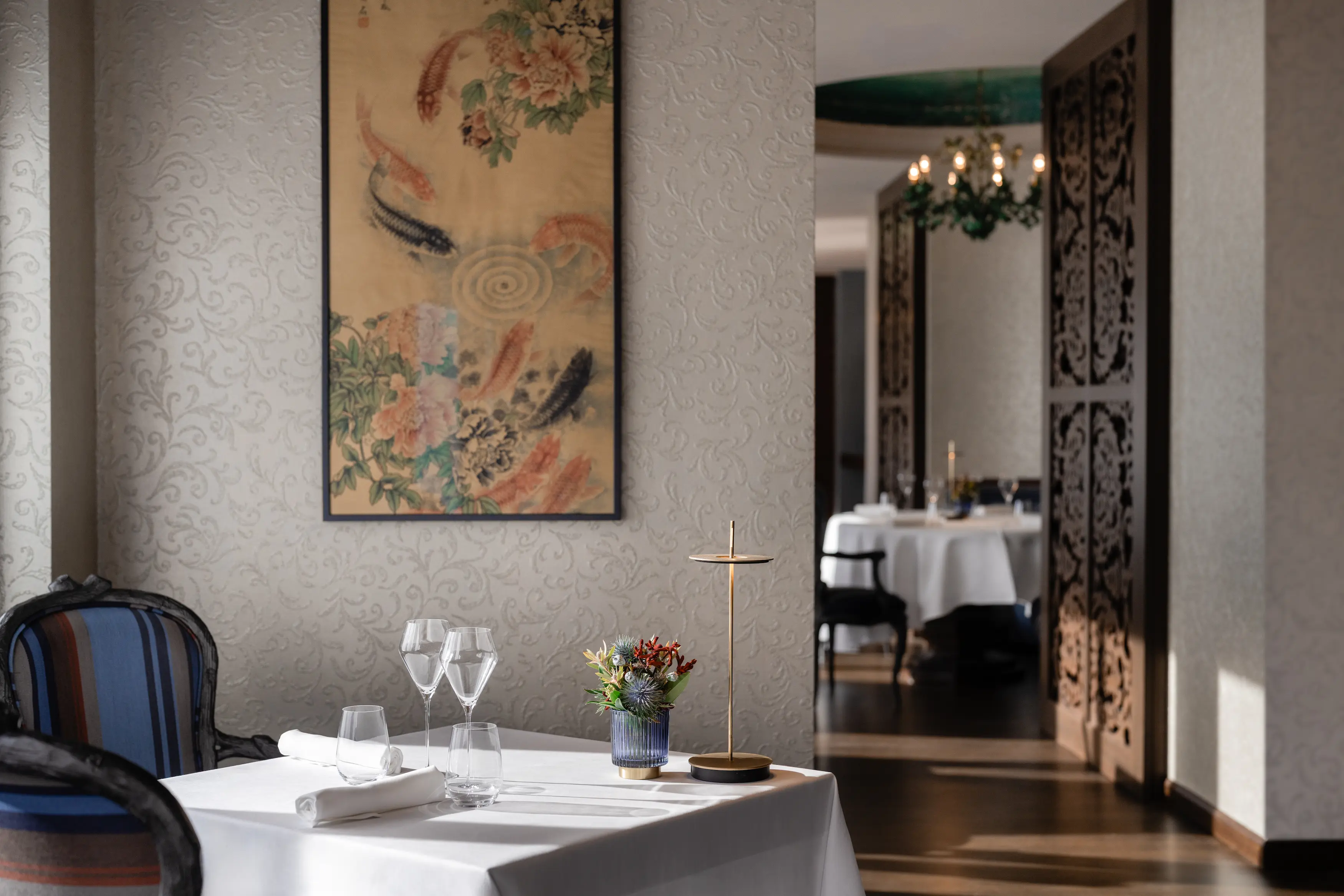 Refined table setting at Da Vittorio with crystal glassware and white linens beneath framed Asian horse painting on textured wall
