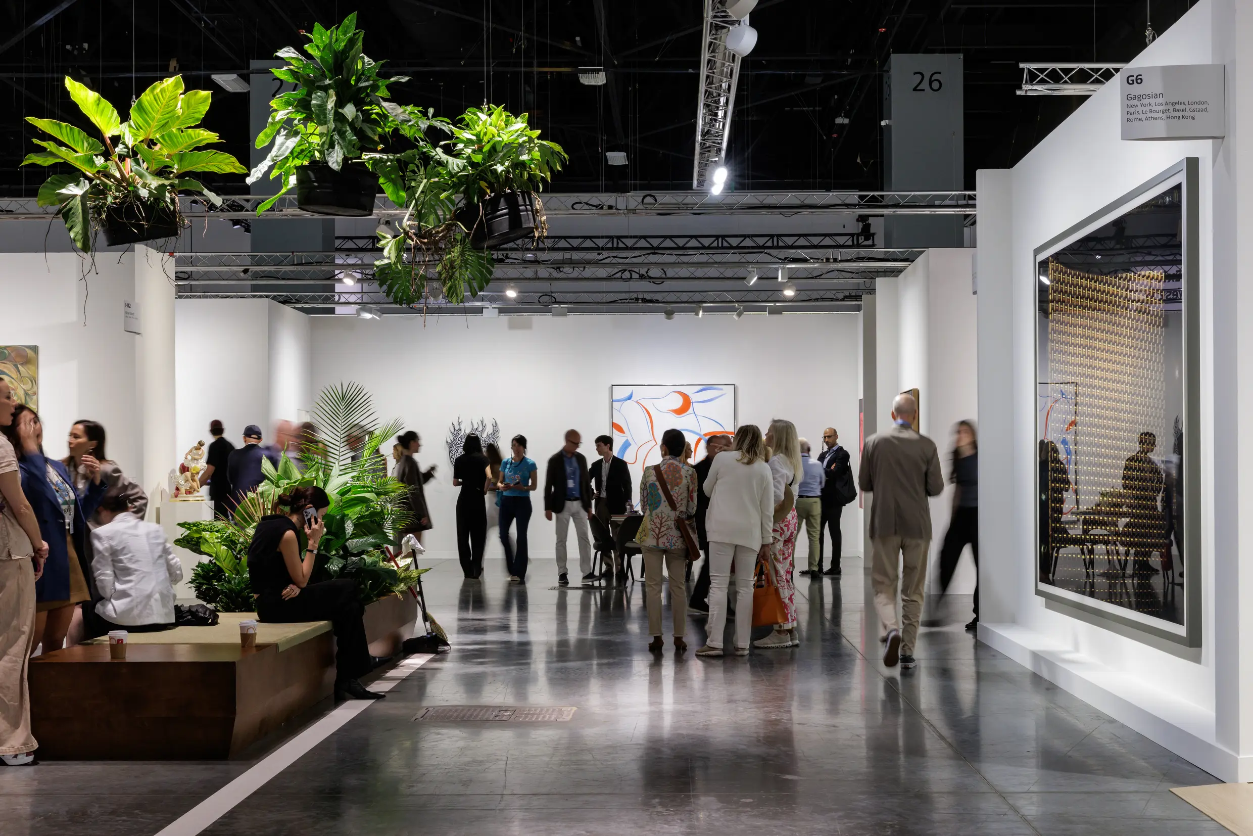 Art Basel Miami Beach 2025 gallery floor showing collectors viewing contemporary artworks near Gagosian booth with tropical plants and modern installations in Miami Beach Convention Center