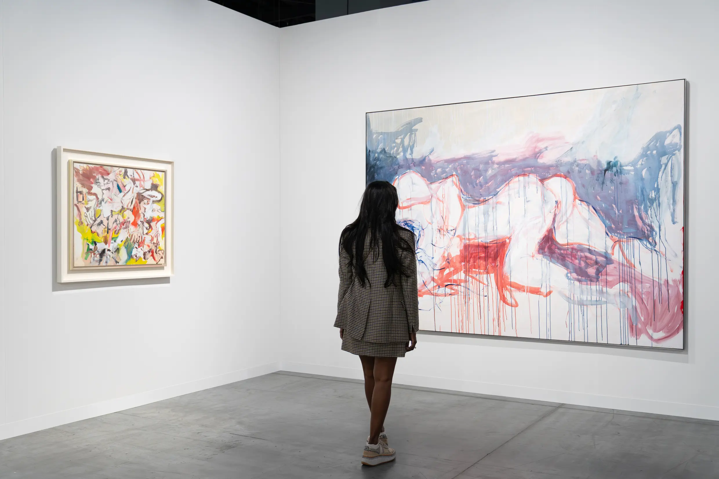 Art Basel Miami Beach 2025 collector examining large abstract expressionist painting with dripping red and blue brushstrokes in minimalist white gallery space