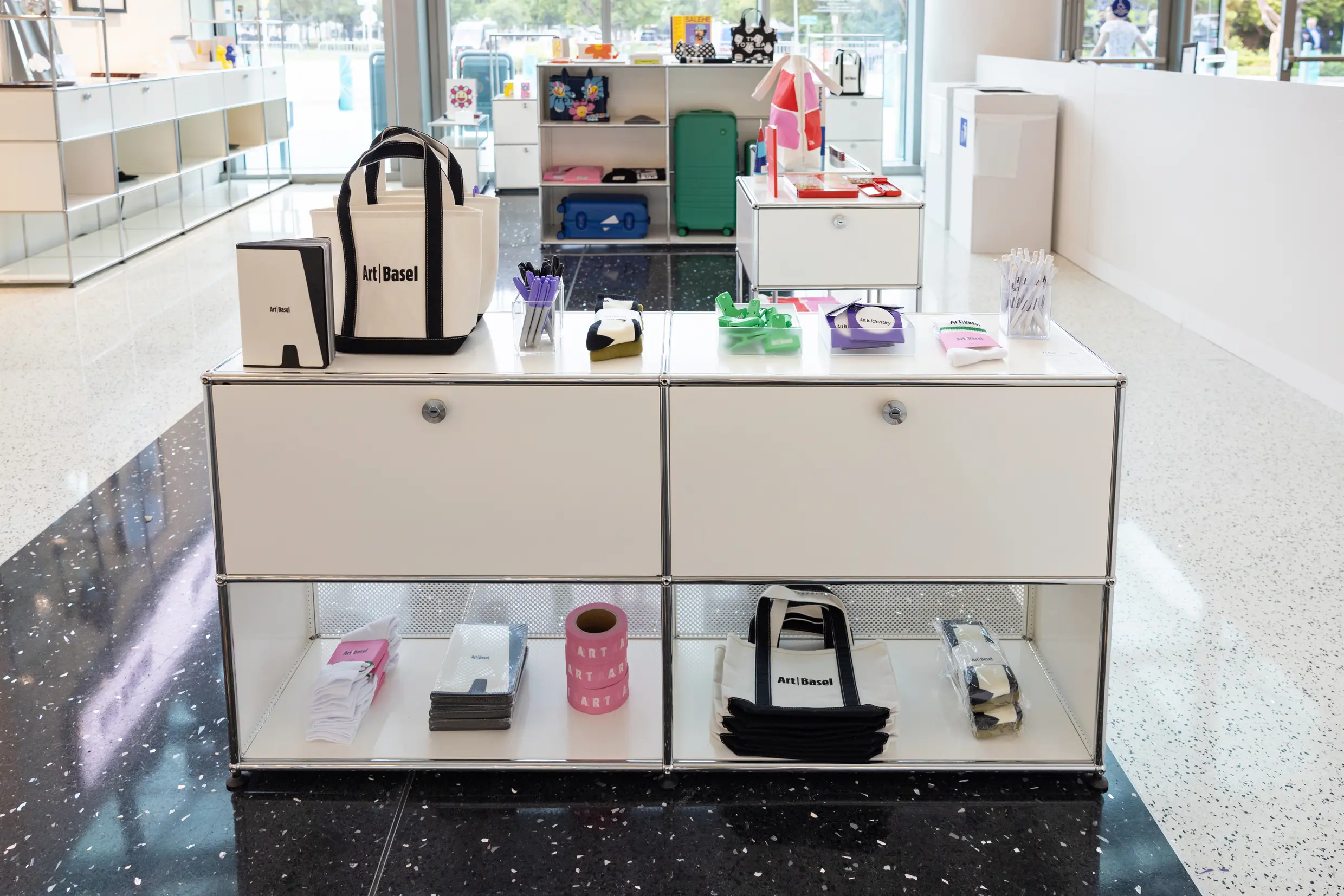 Art Basel Miami Beach 2025 official shop display featuring Art Basel branded tote bags, collectible accessories, artist collaborations, and limited-edition merchandise on modern shelving