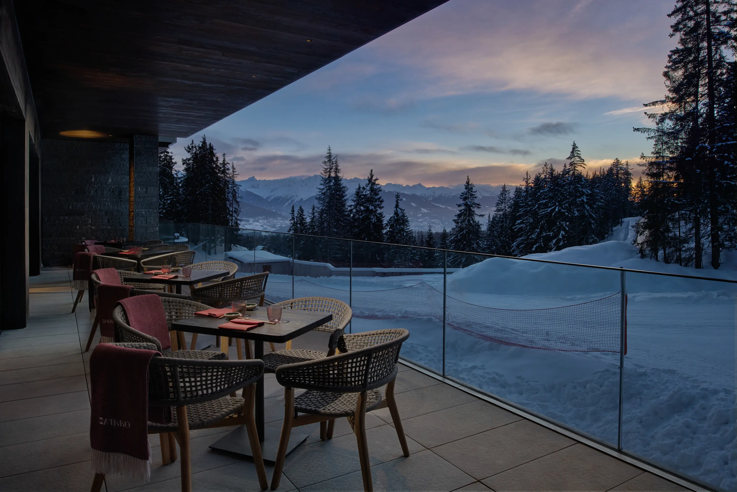Byakko restaurant terrace at Six Senses Crans-Montana featuring outdoor dining with panoramic Valais Alps views at twilight, contemporary design with alpine forest setting