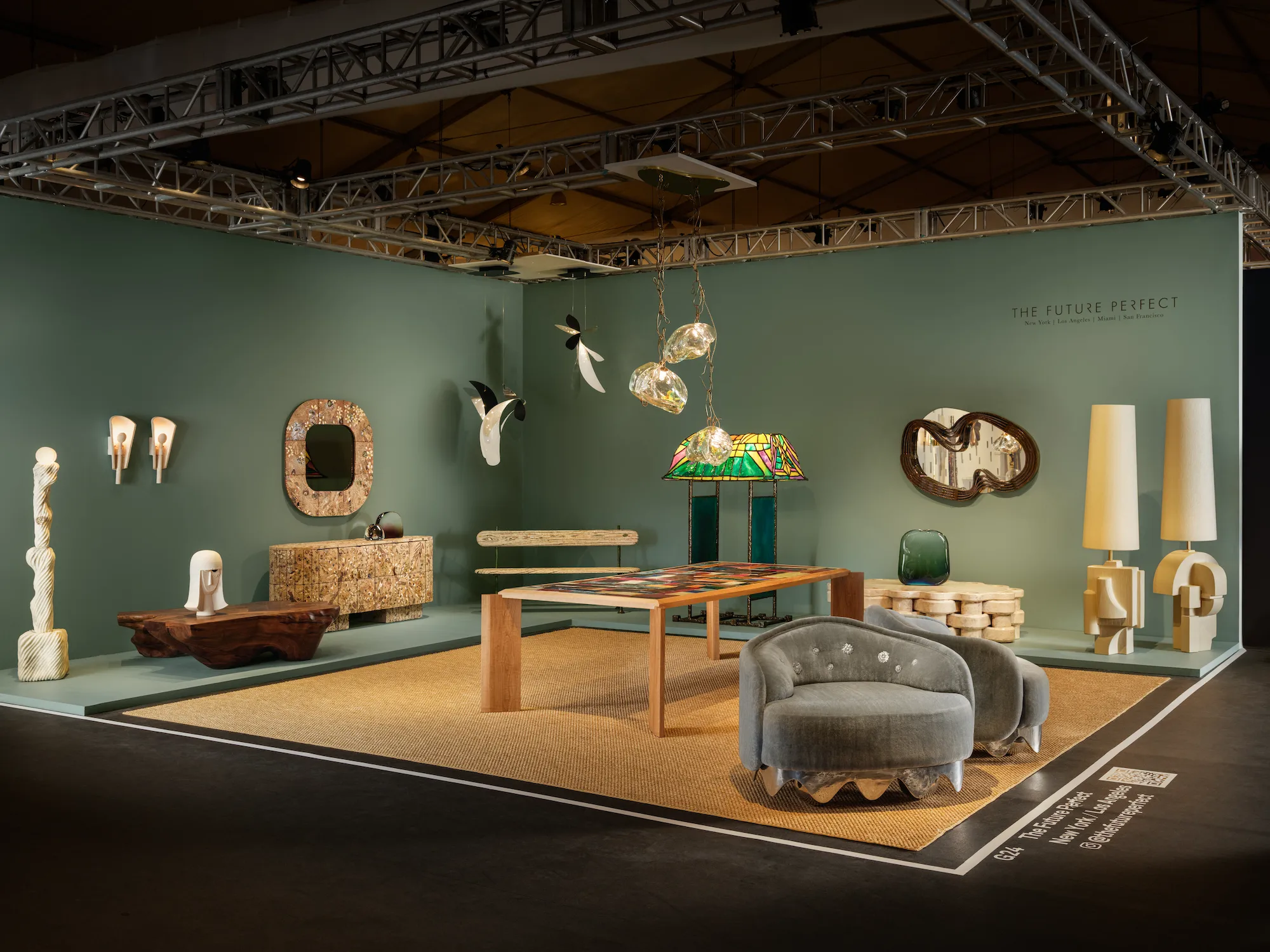 The Future Perfect gallery booth at Design Miami 2025 with sage green walls displaying sculptural lighting, ceramic vessels, stained glass lamp, carved wood furniture, and contemporary collectible design objects