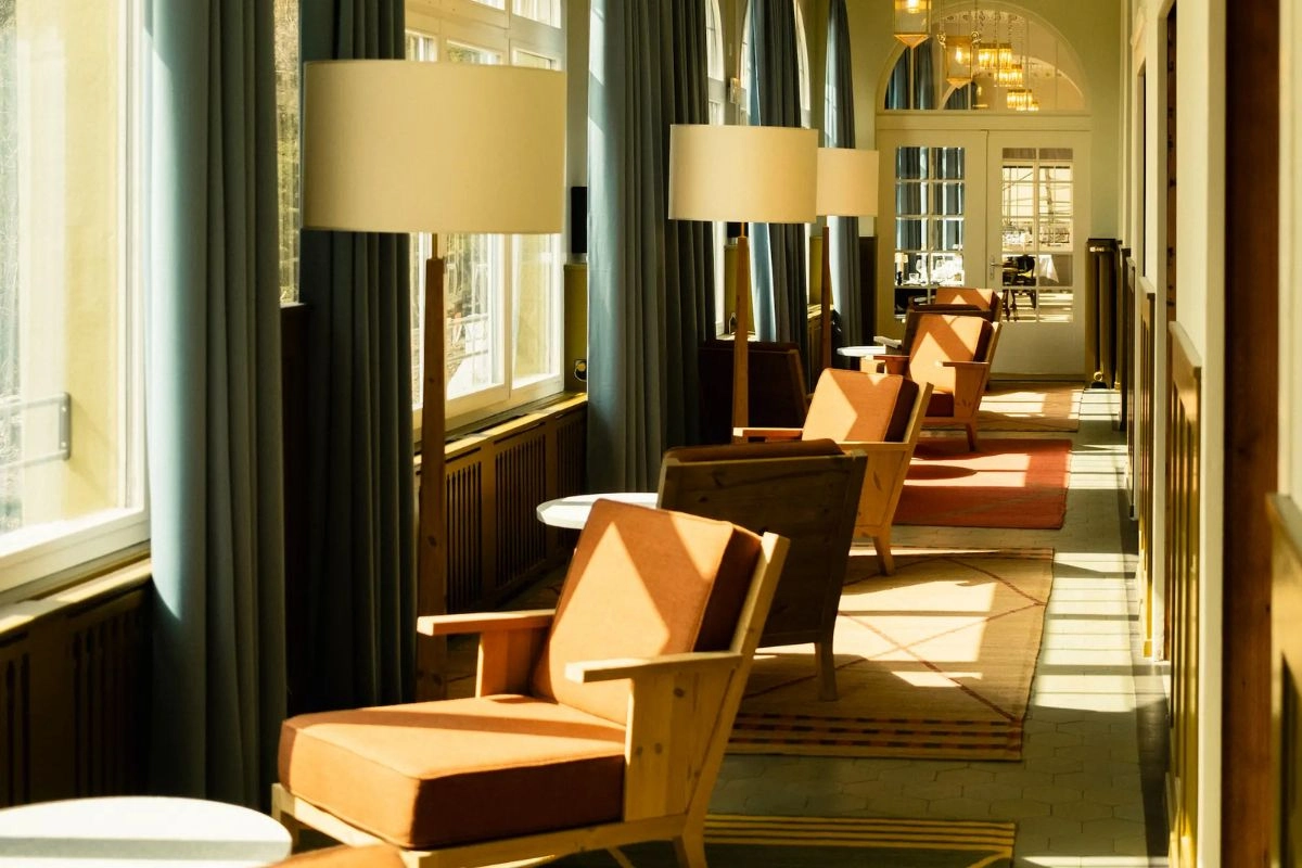 Grand Hotel Belvedere lobby featuring Belle Époque architecture with Art Nouveau arches, period pendant lighting, modern seating and sunlit elegant interiors in Wengen