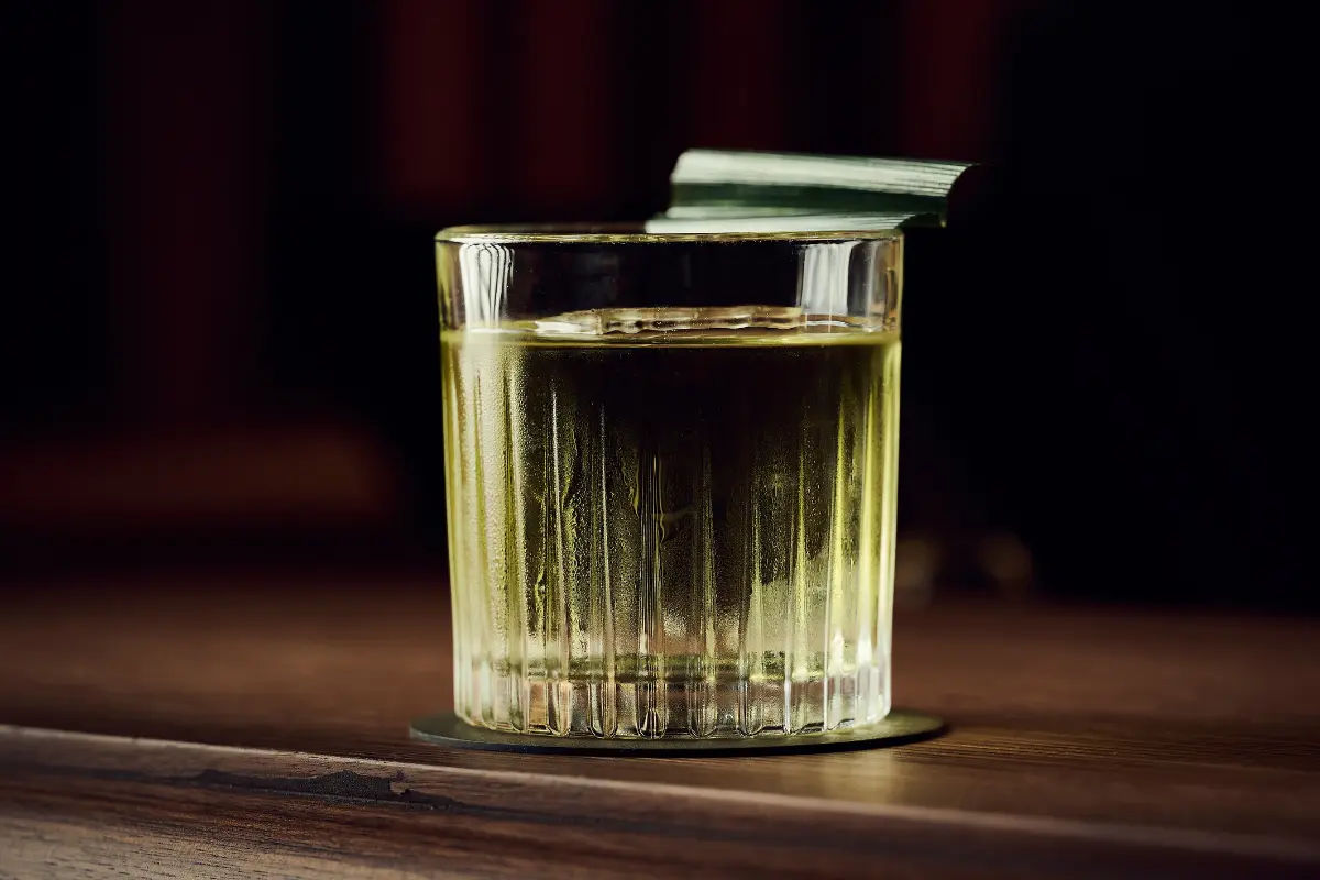 Carefully crafted cocktail in cut crystal glassware with herb garnish showcasing thoughtful beverage program at IGNIV by Andreas Caminada Andermatt