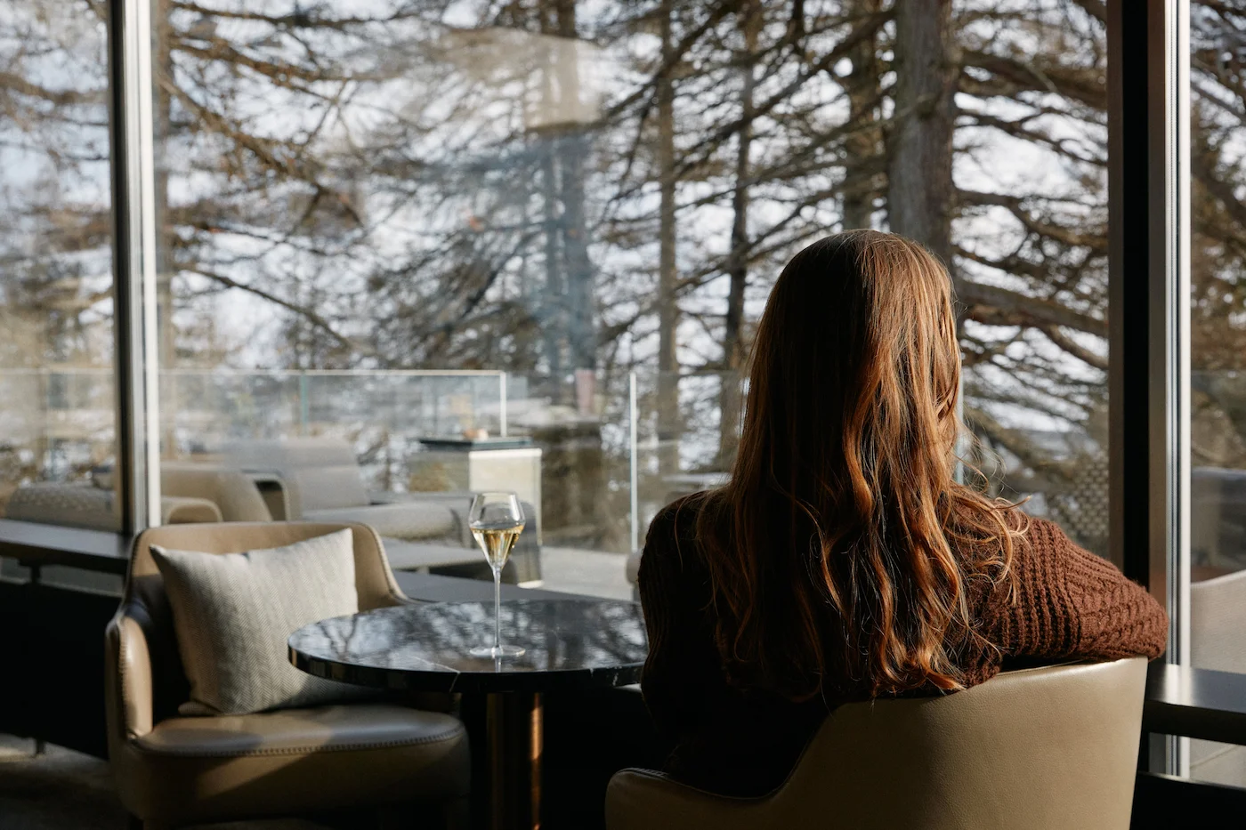 Guest enjoying champagne with panoramic alpine forest views at 7132 Hotel luxury spa resort in Vals Switzerland
